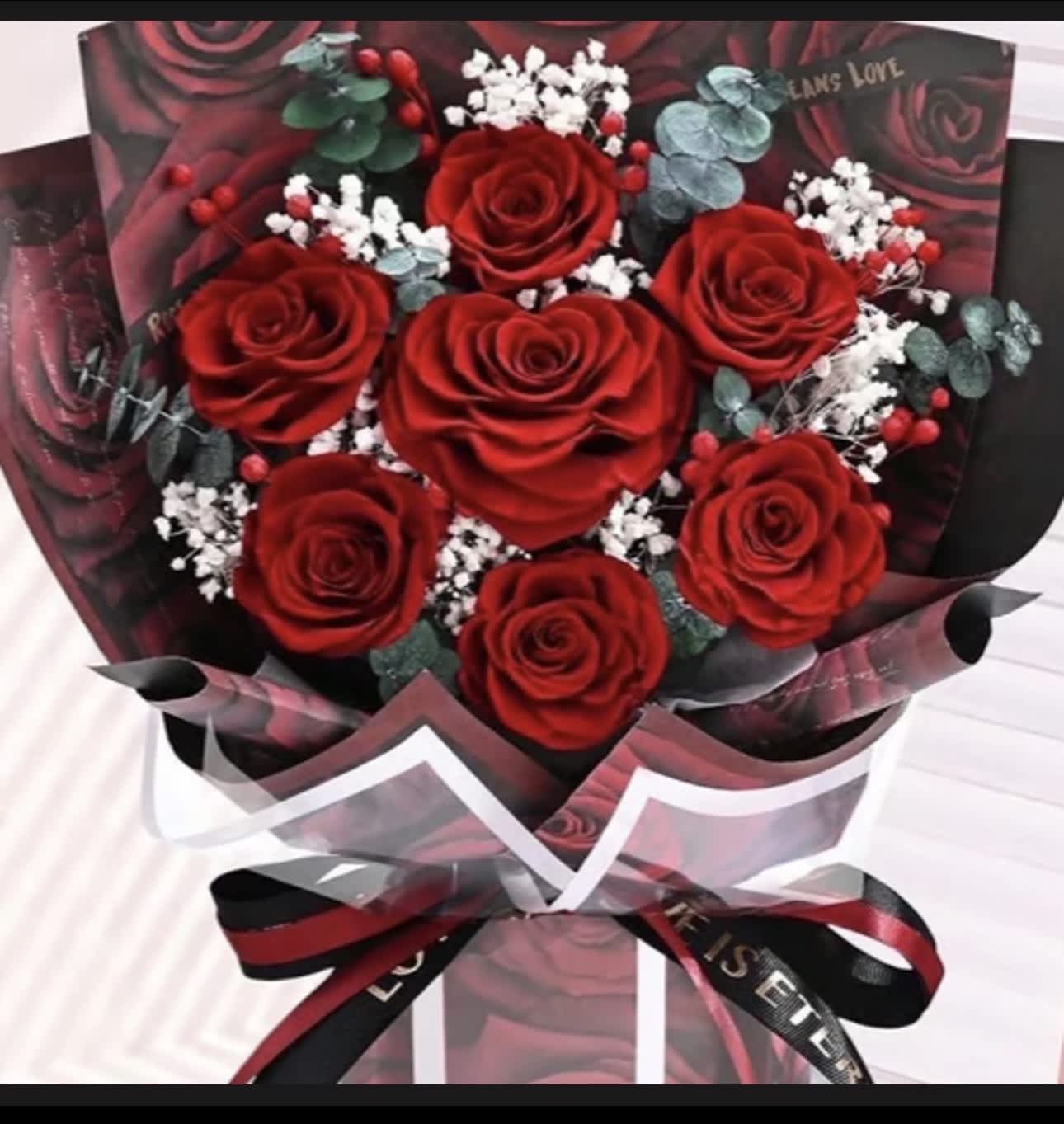 Bouquet of red roses with white filler flowers and dark wrapping
