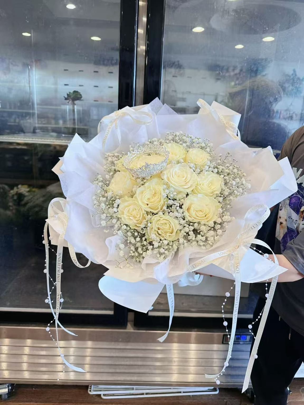 Bouquet of pale yellow roses wrapped in white paper with ribbon accents