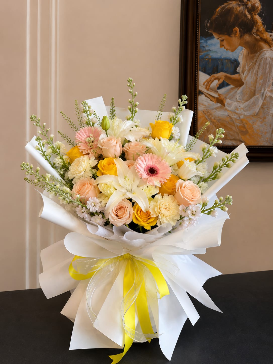 Bouquet of pink, yellow, and white flowers wrapped in white paper with a yellow ribbon