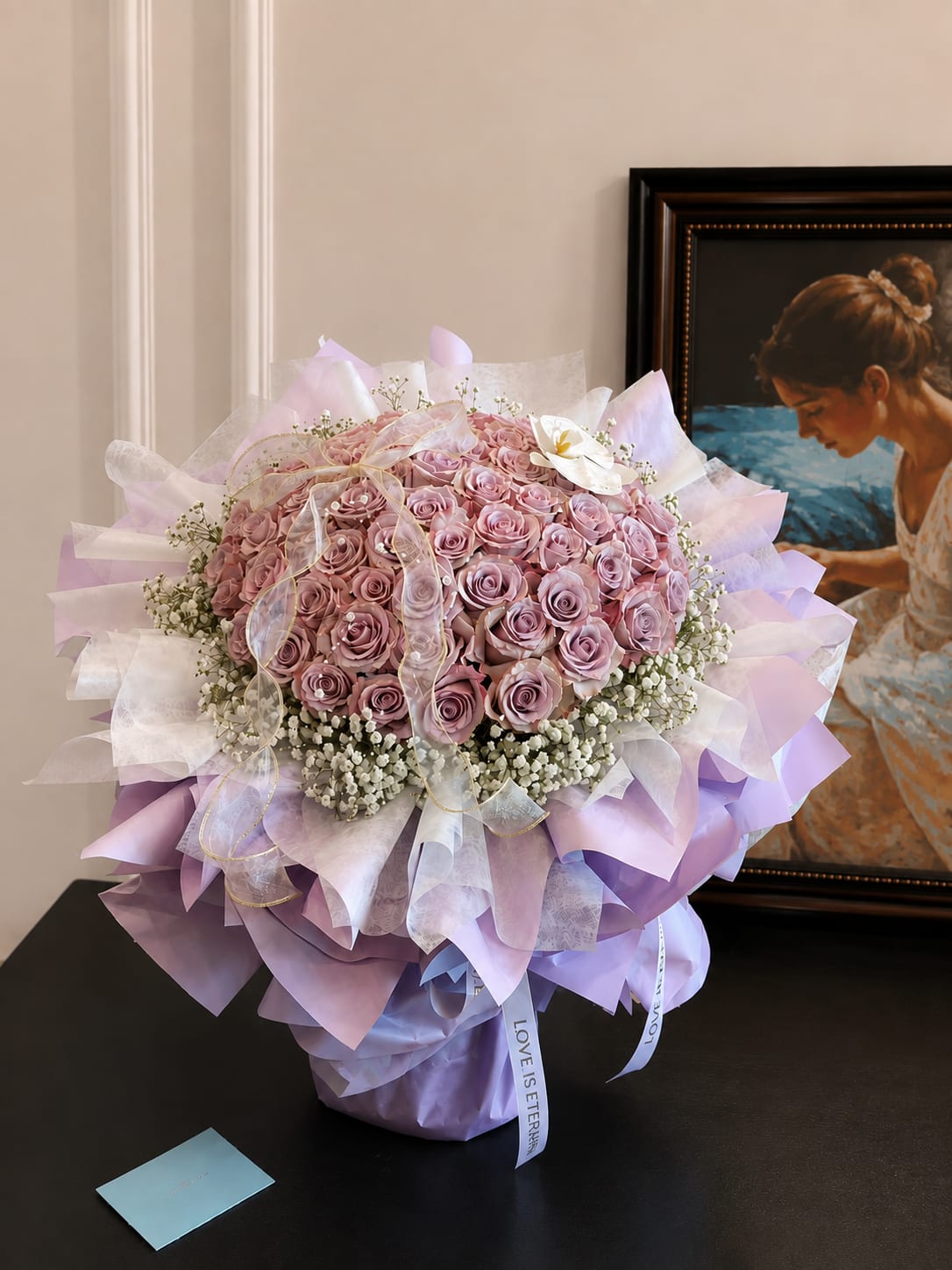 Large bouquet of pink roses wrapped in lavender paper with a ribbon