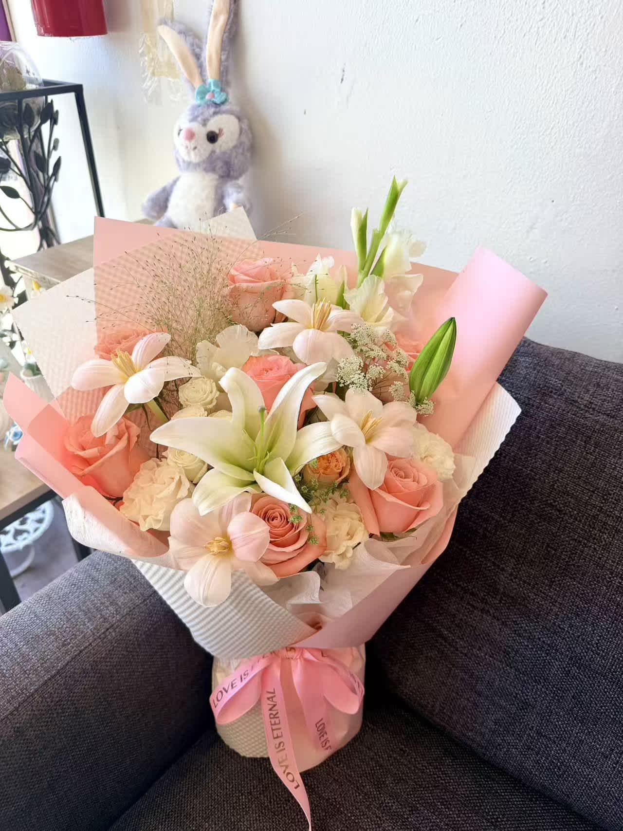 Pink and white bouquet with roses and lilies wrapped in pastel paper