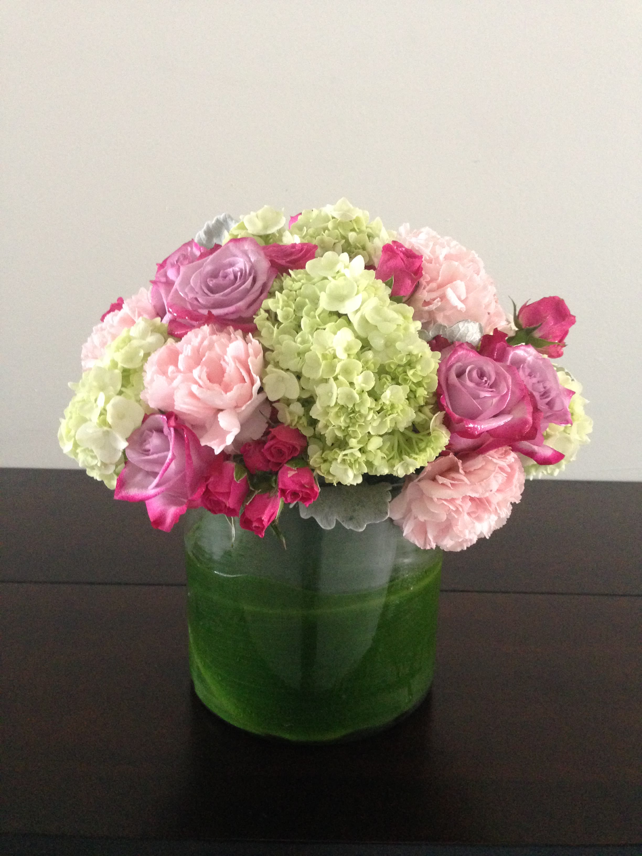 Pink and lavender flowers arranged in a green glass vase