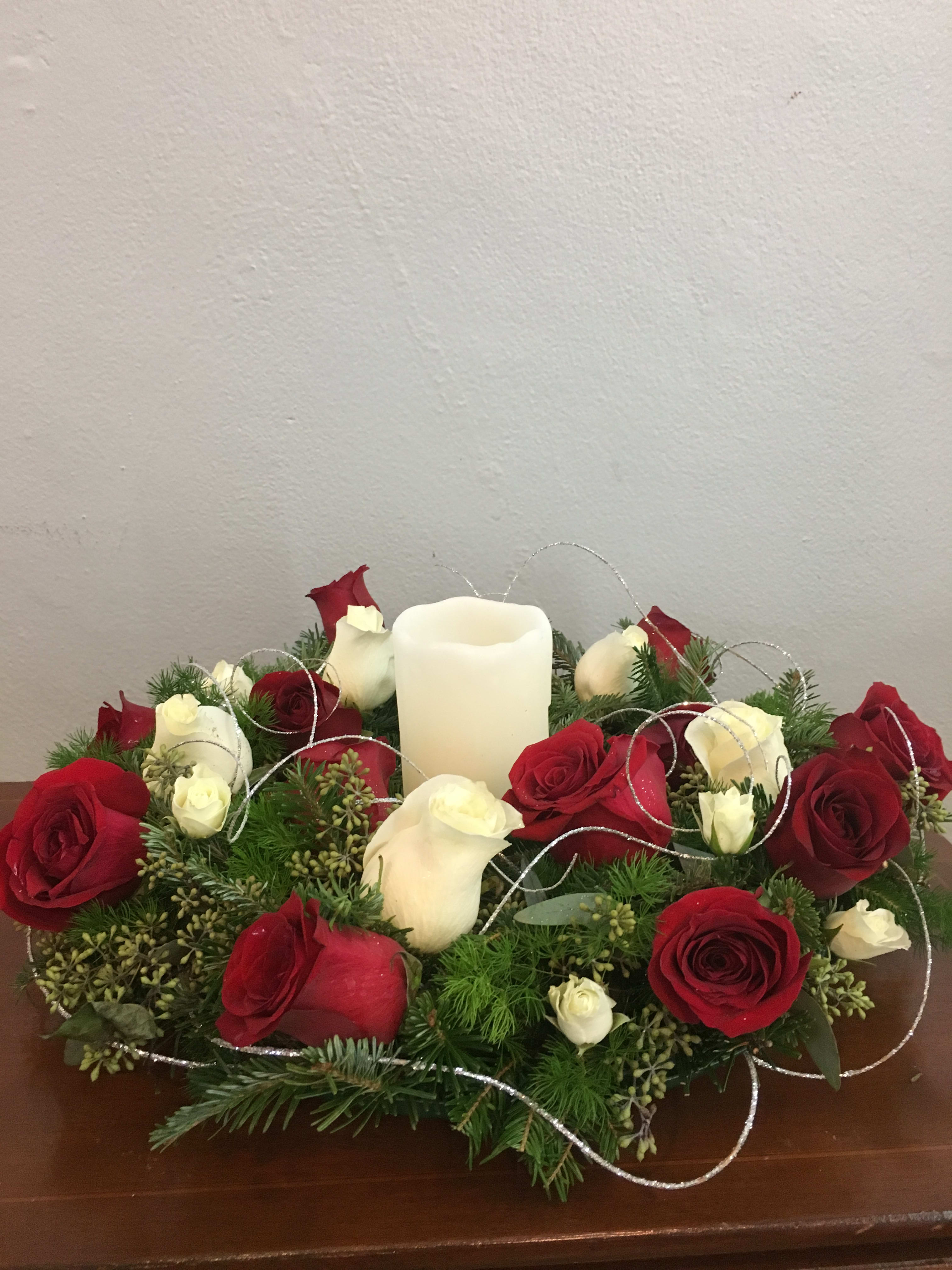 Red and white roses arranged around a white pillar candle
