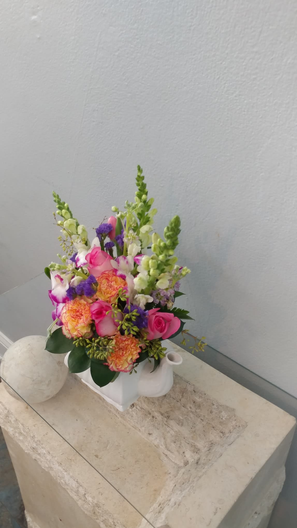 Pink and orange mixed flower arrangement in a white ceramic container