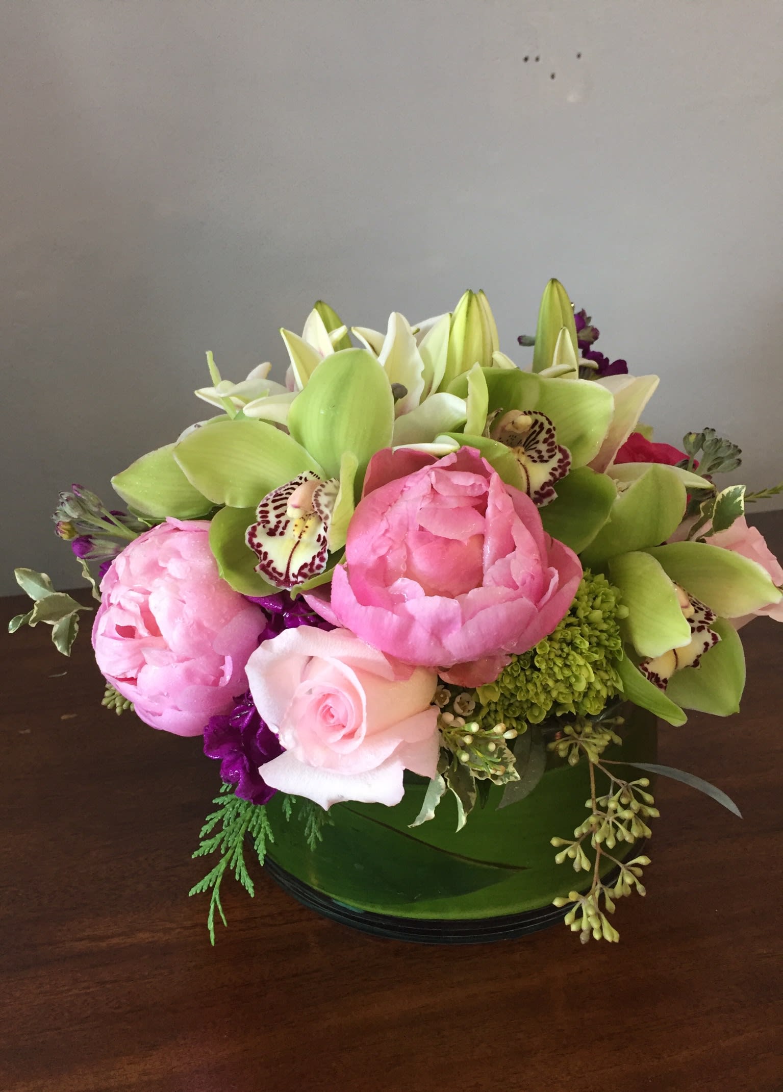 Pink peonies and roses with green orchids in a low vase