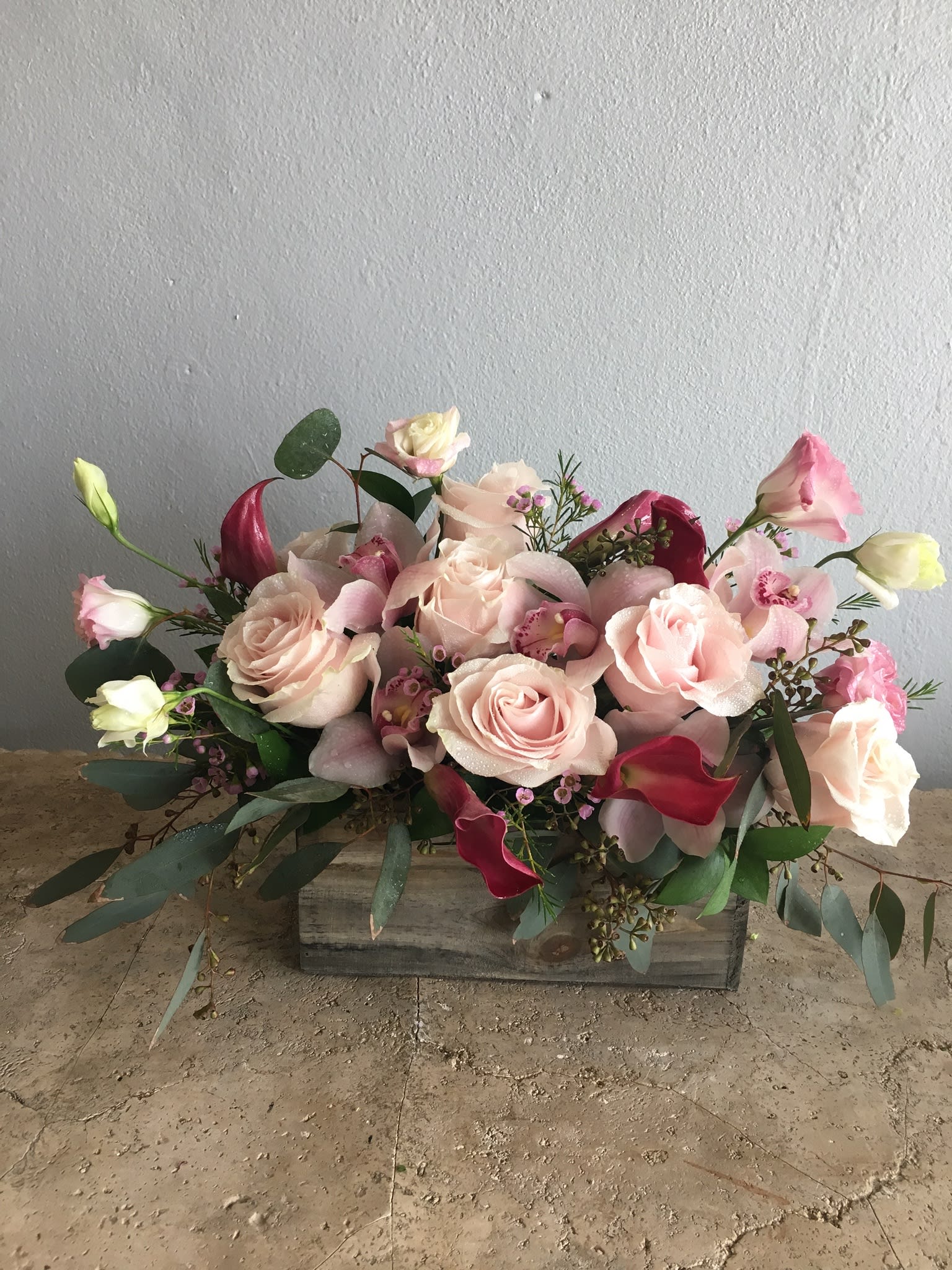 Pink roses and calla lilies arranged in a wooden box