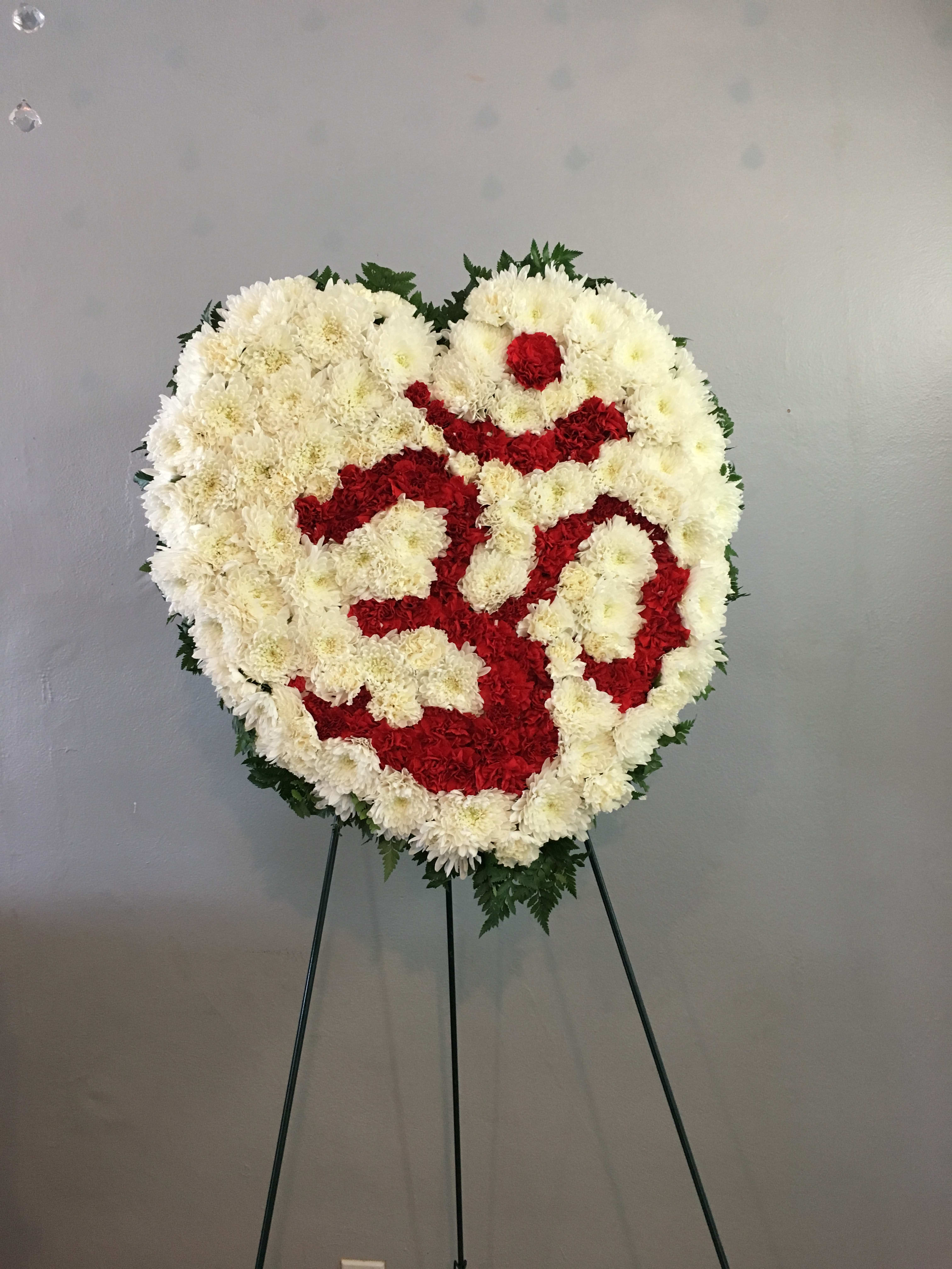 Heart-shaped floral wreath of white and red flowers on a stand