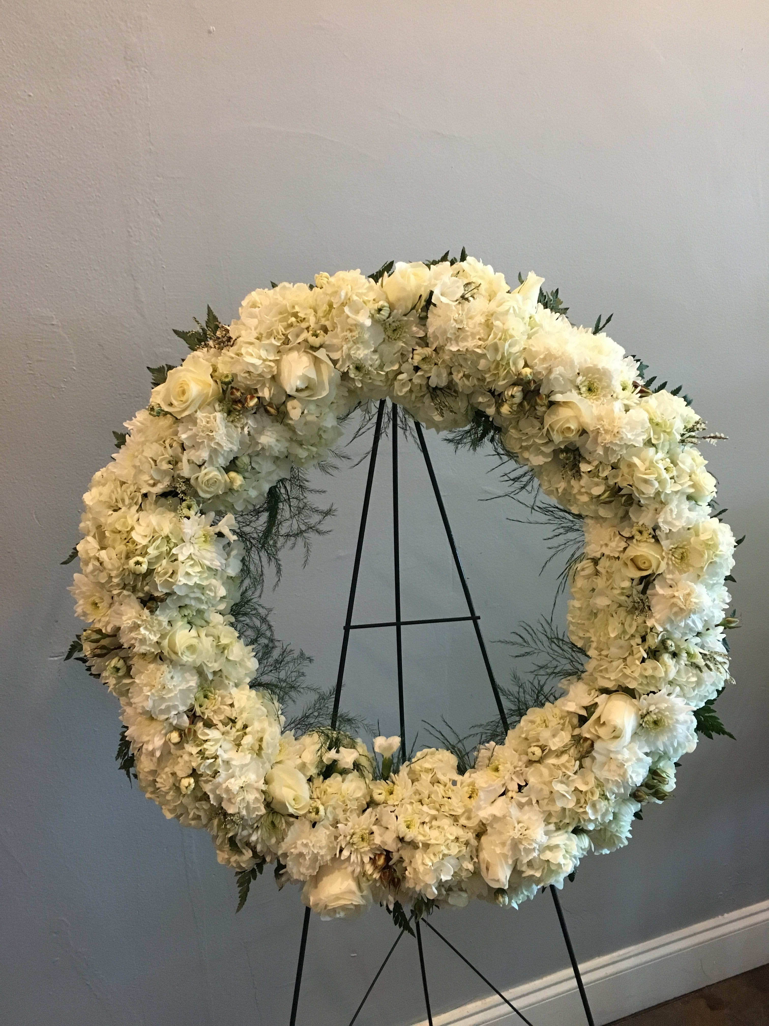 White floral wreath on a black stand