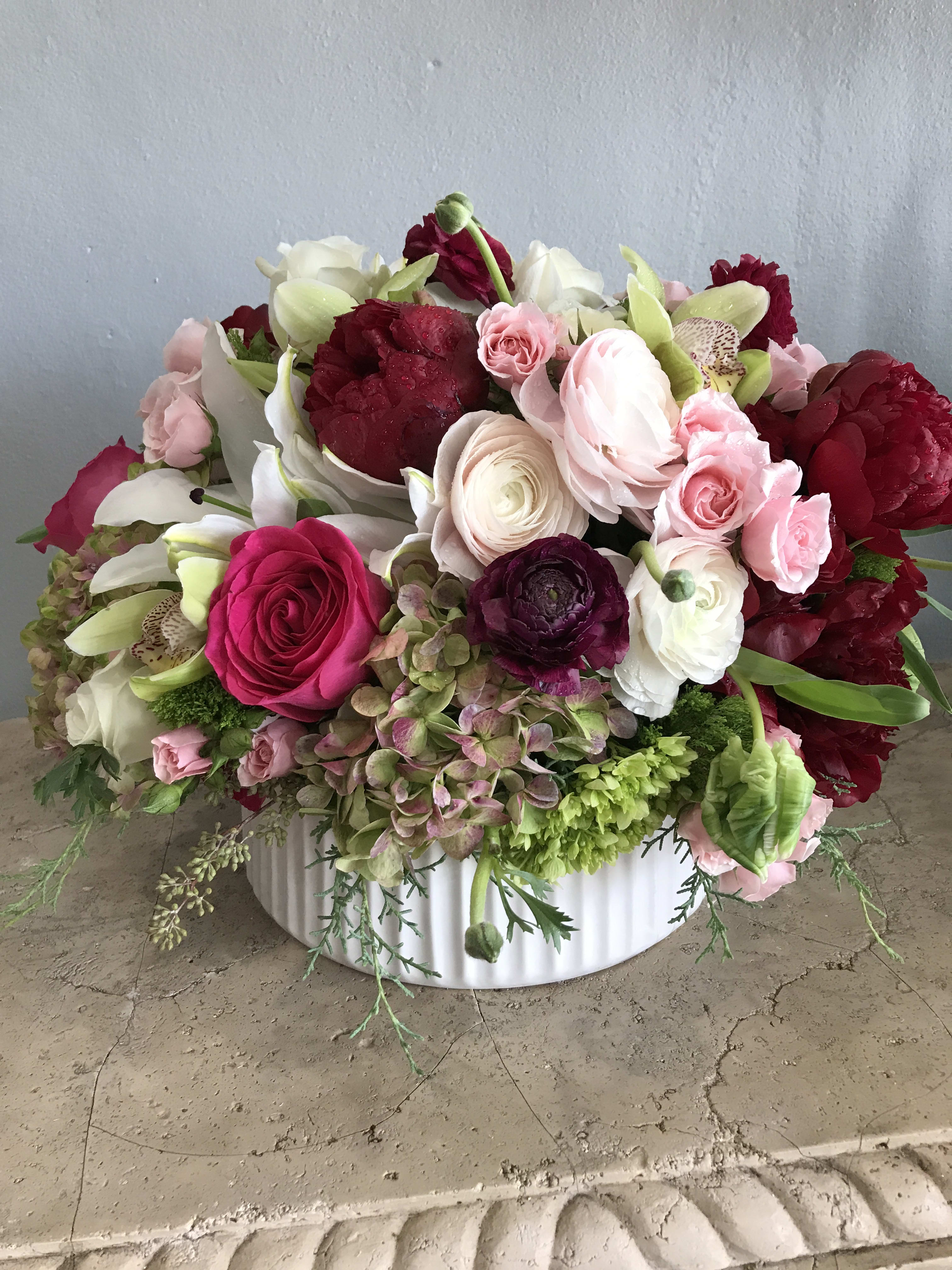 Mixed pink, white, and burgundy flowers in a white bowl vase