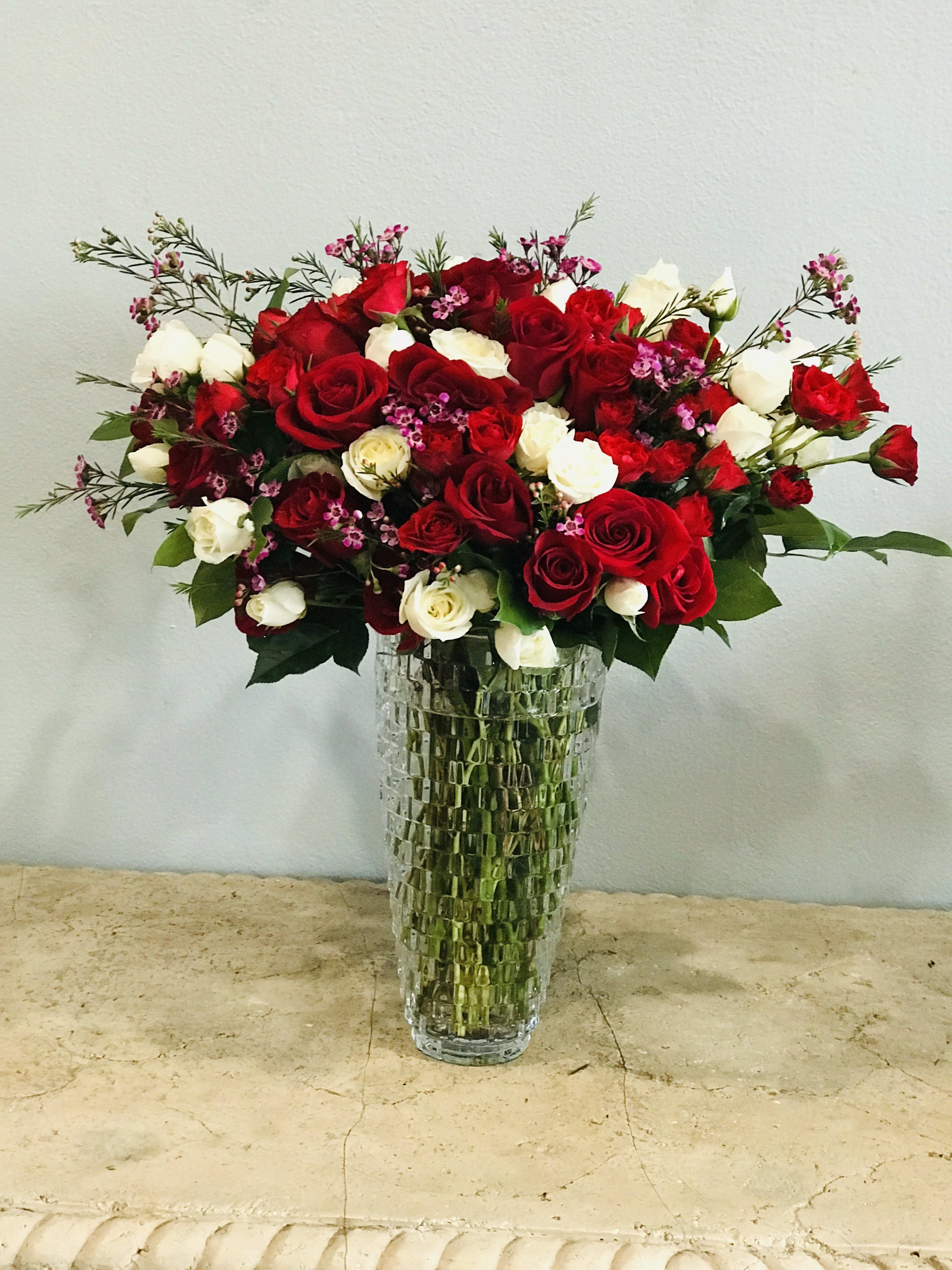 Red and white roses arranged in a tall glass vase