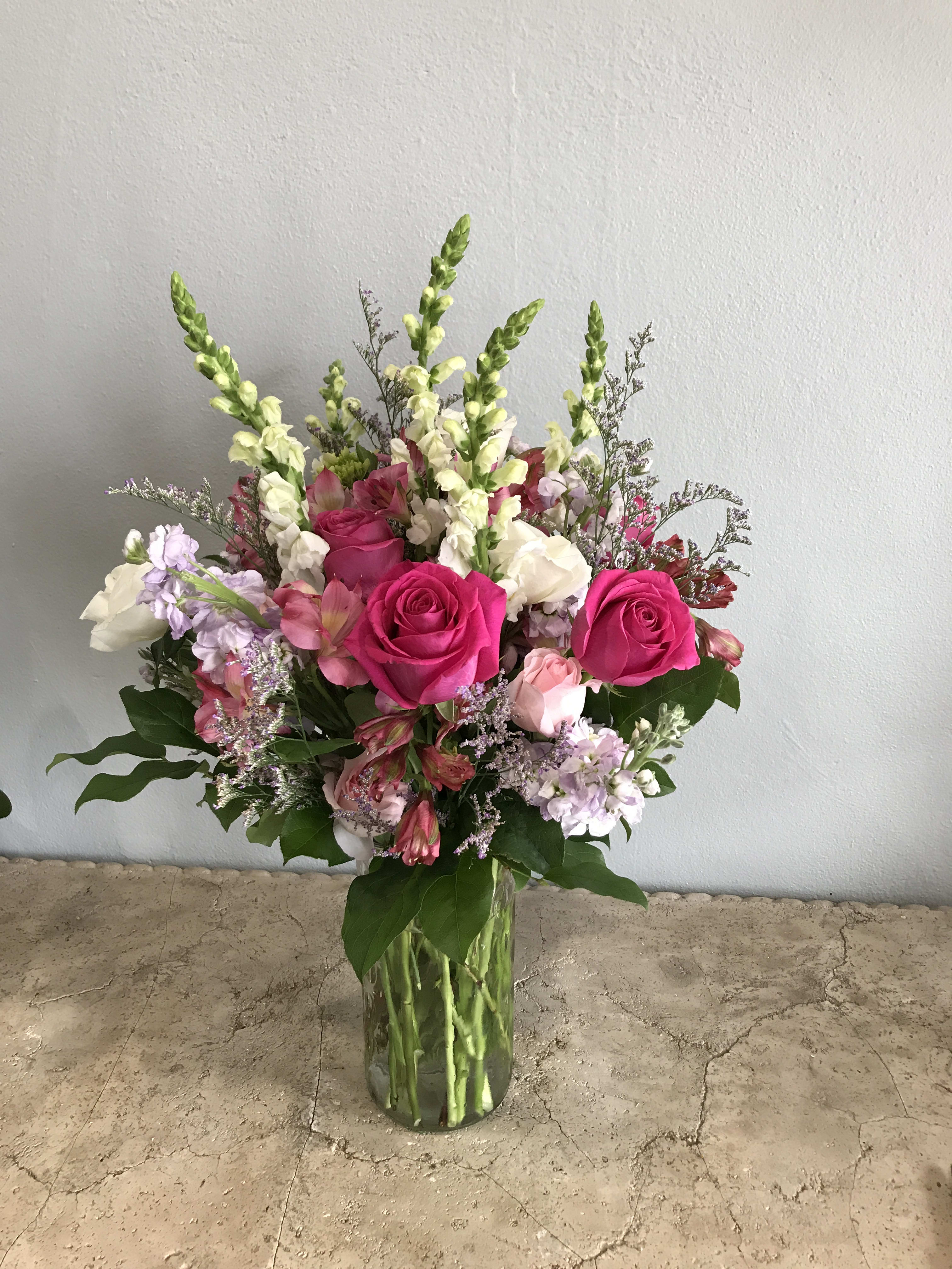 Bouquet of pink roses, snapdragons, and mixed blooms in a clear glass vase