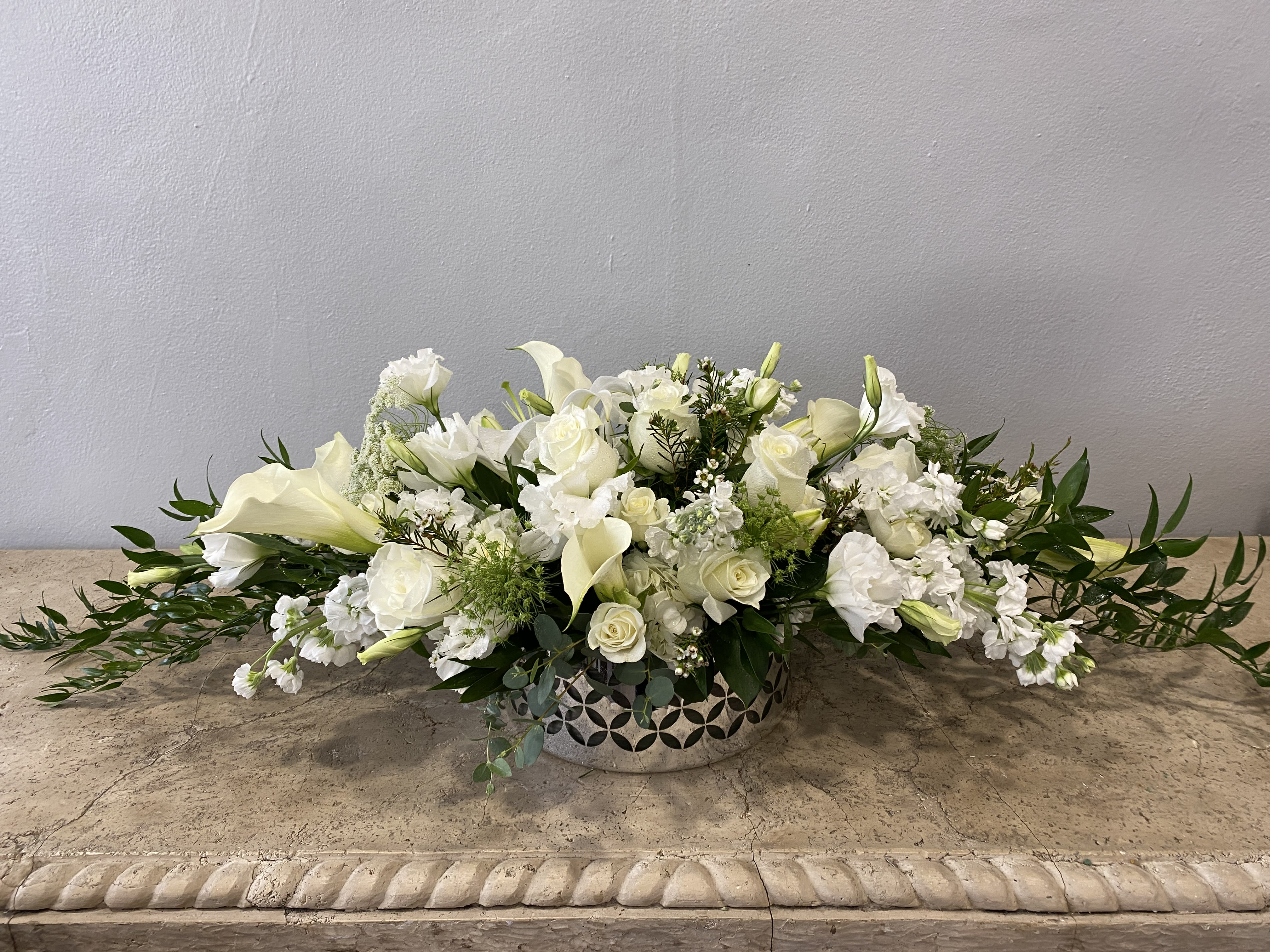 Low white floral arrangement in a decorative silver bowl