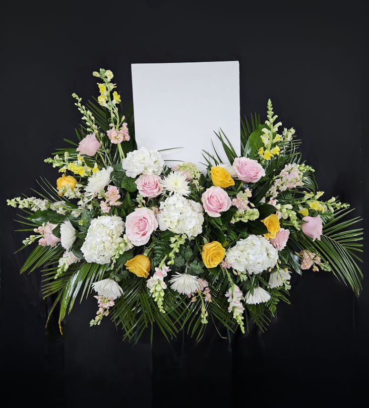 Floral standing spray with pink and yellow roses and white blooms