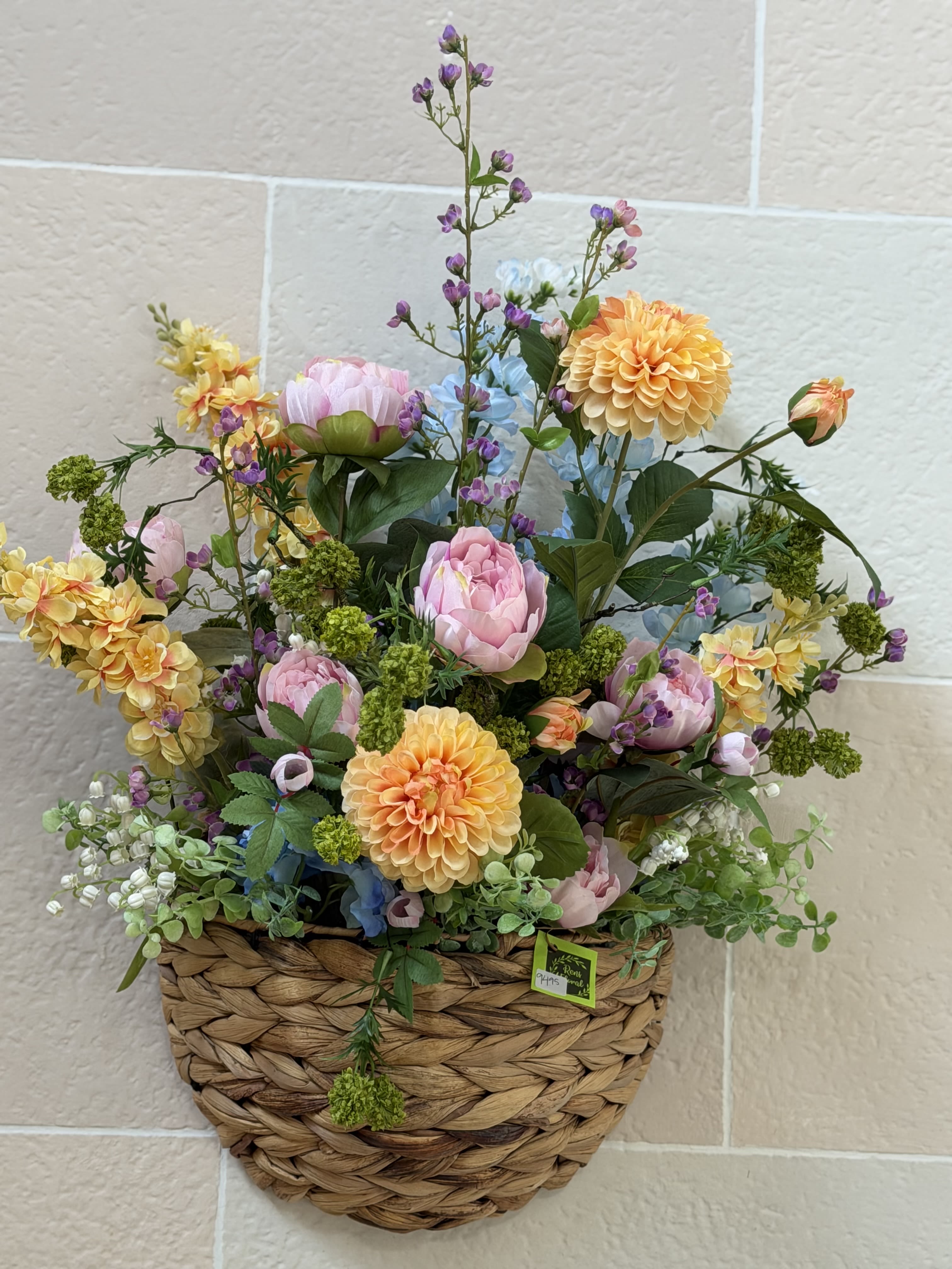 Artificial Wall Hanger  - A woven wall hanger basket filled with pastel artificial flowers. 