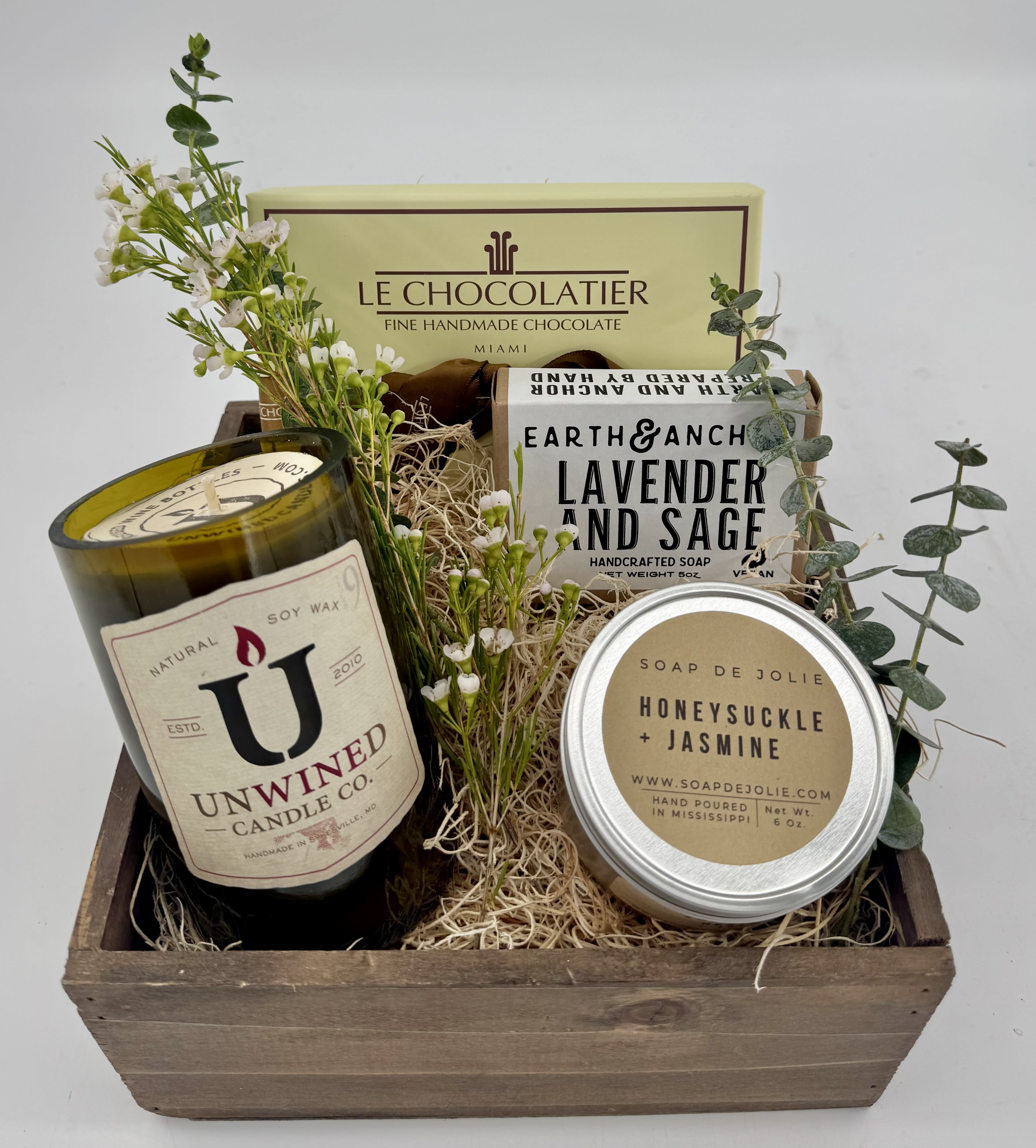 Gift basket with candles, soaps, chocolates, and small white flowers