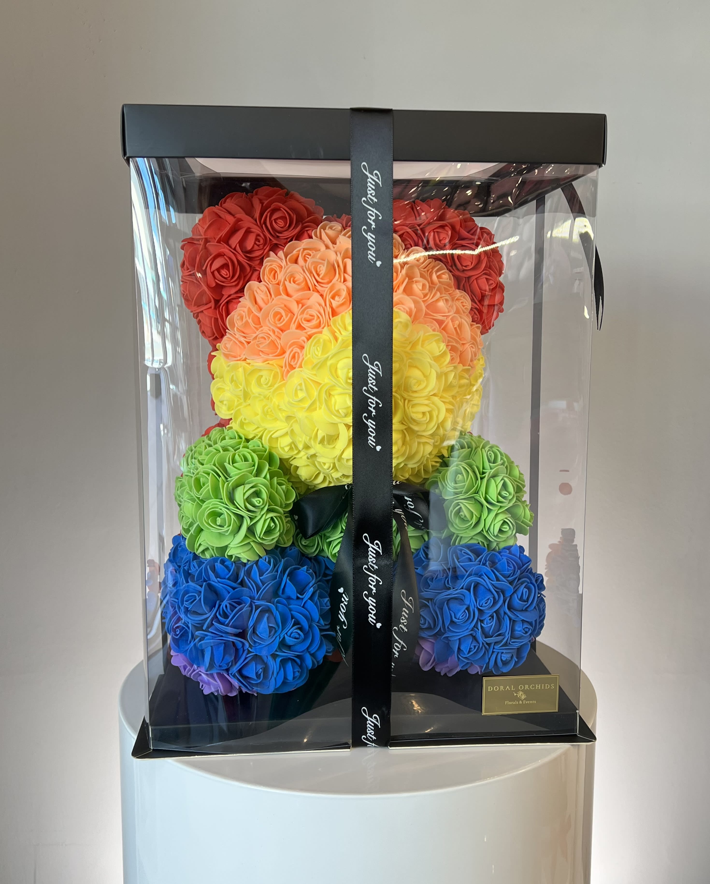 Rainbow teddy bear made of roses in a clear gift box