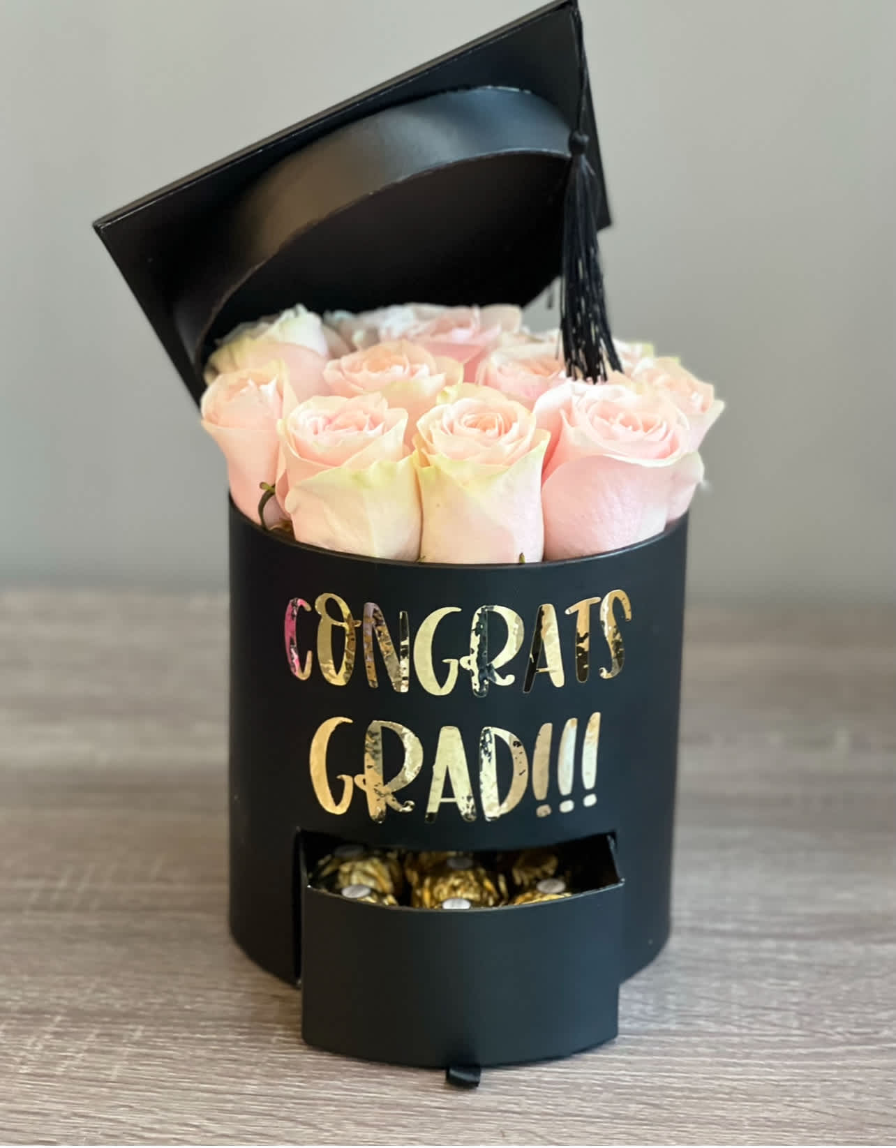 Pink roses in a black graduation box with a tassel