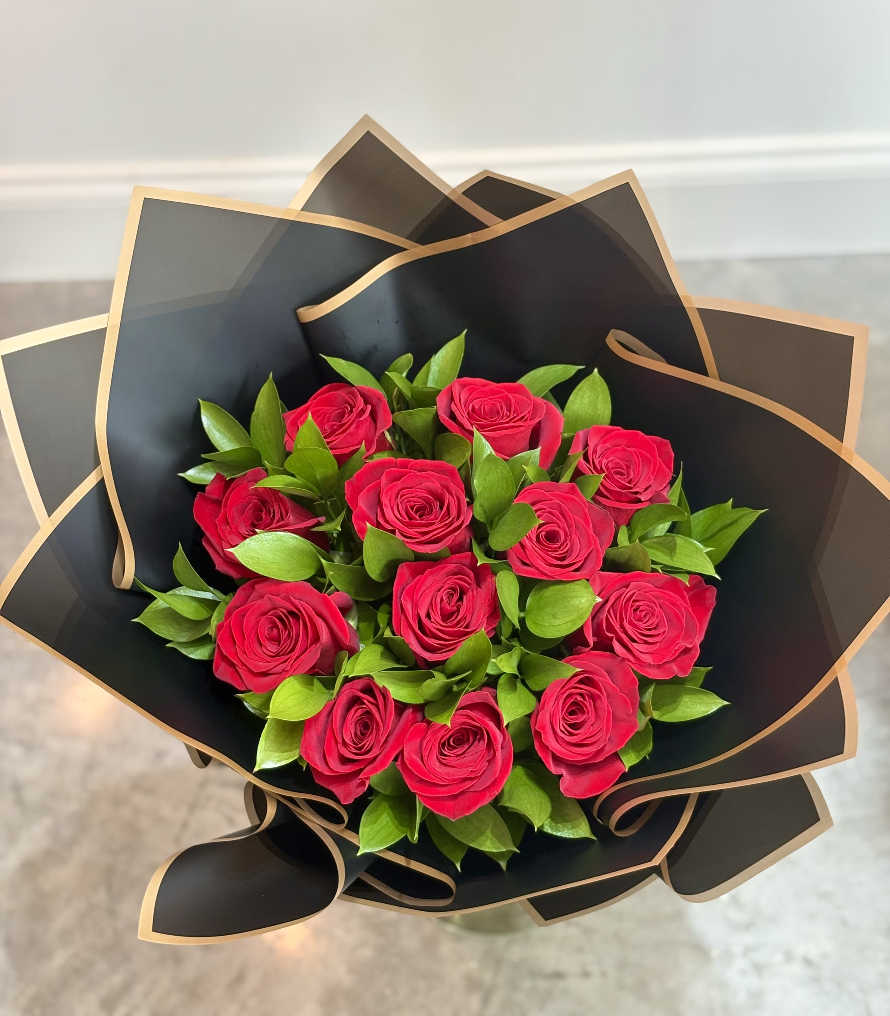 Bouquet of hot pink roses wrapped in black paper with gold trim
