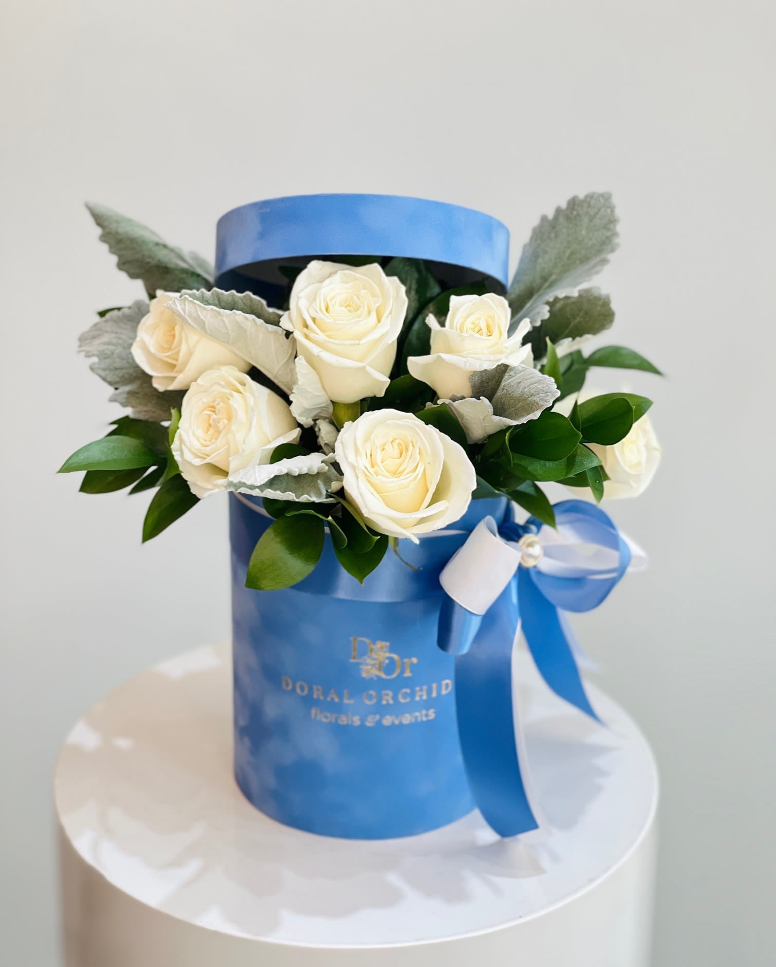 White roses arranged in a blue gift box with a ribbon