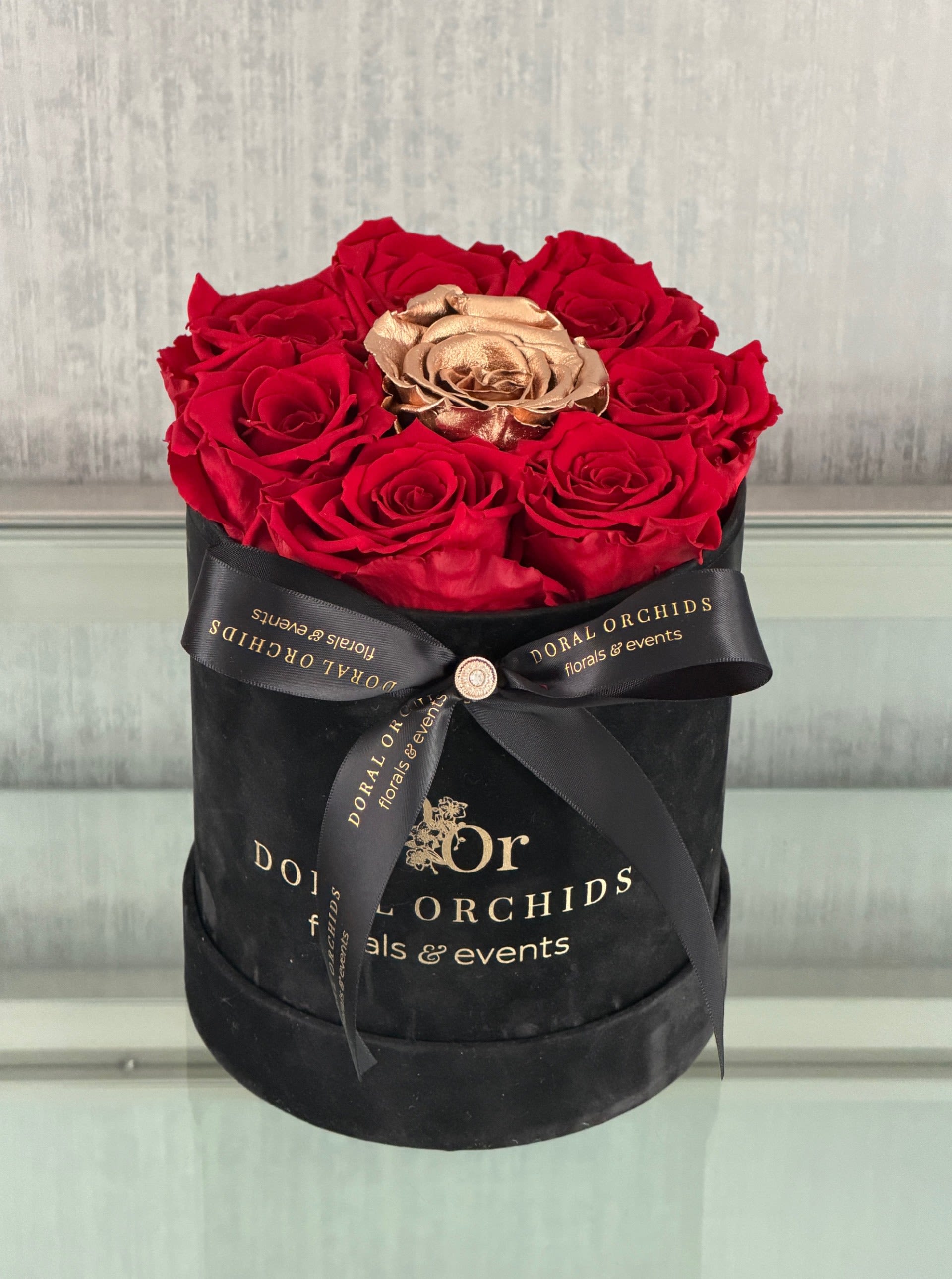 Red roses and a gold rose in a black hatbox with a ribbon
