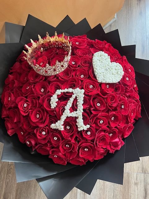 Round bouquet of red roses with a crown and white heart accents
