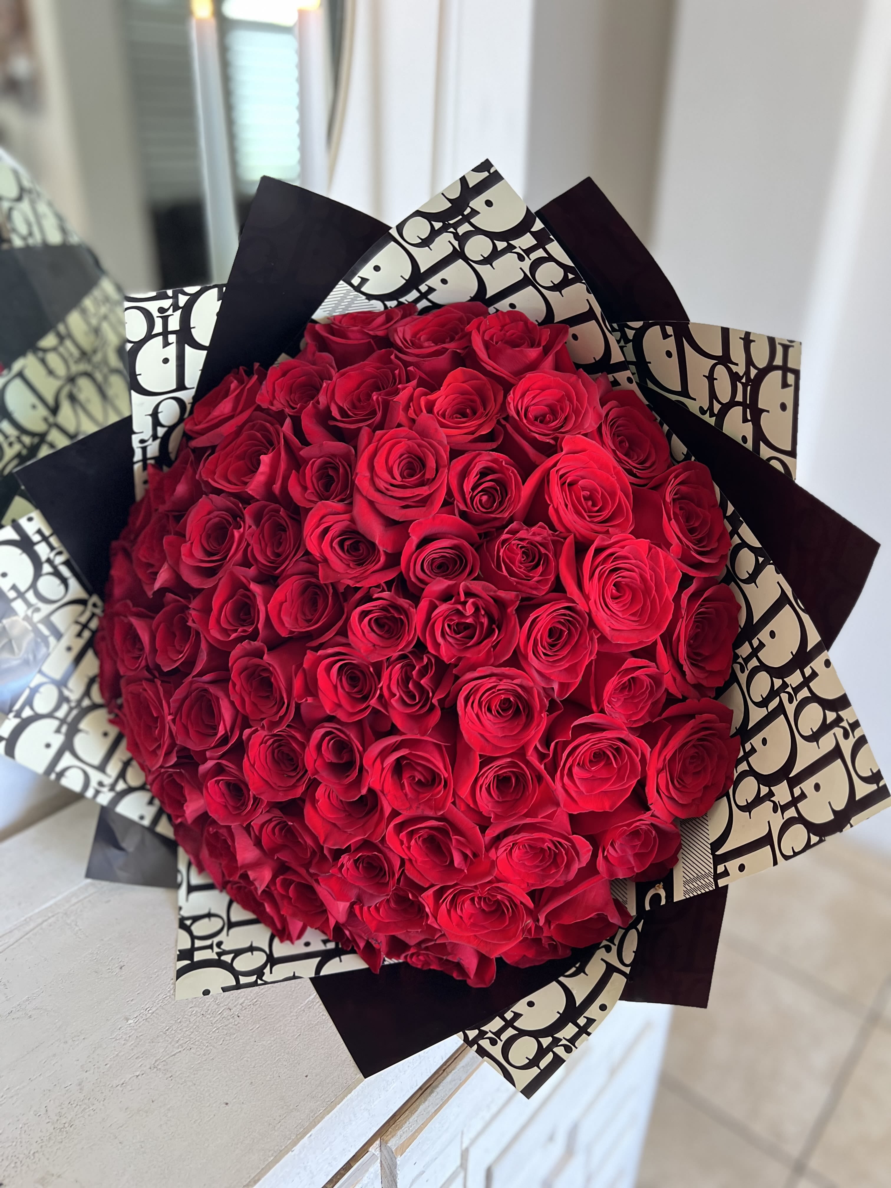 Large bouquet of red roses wrapped in black-and-white paper