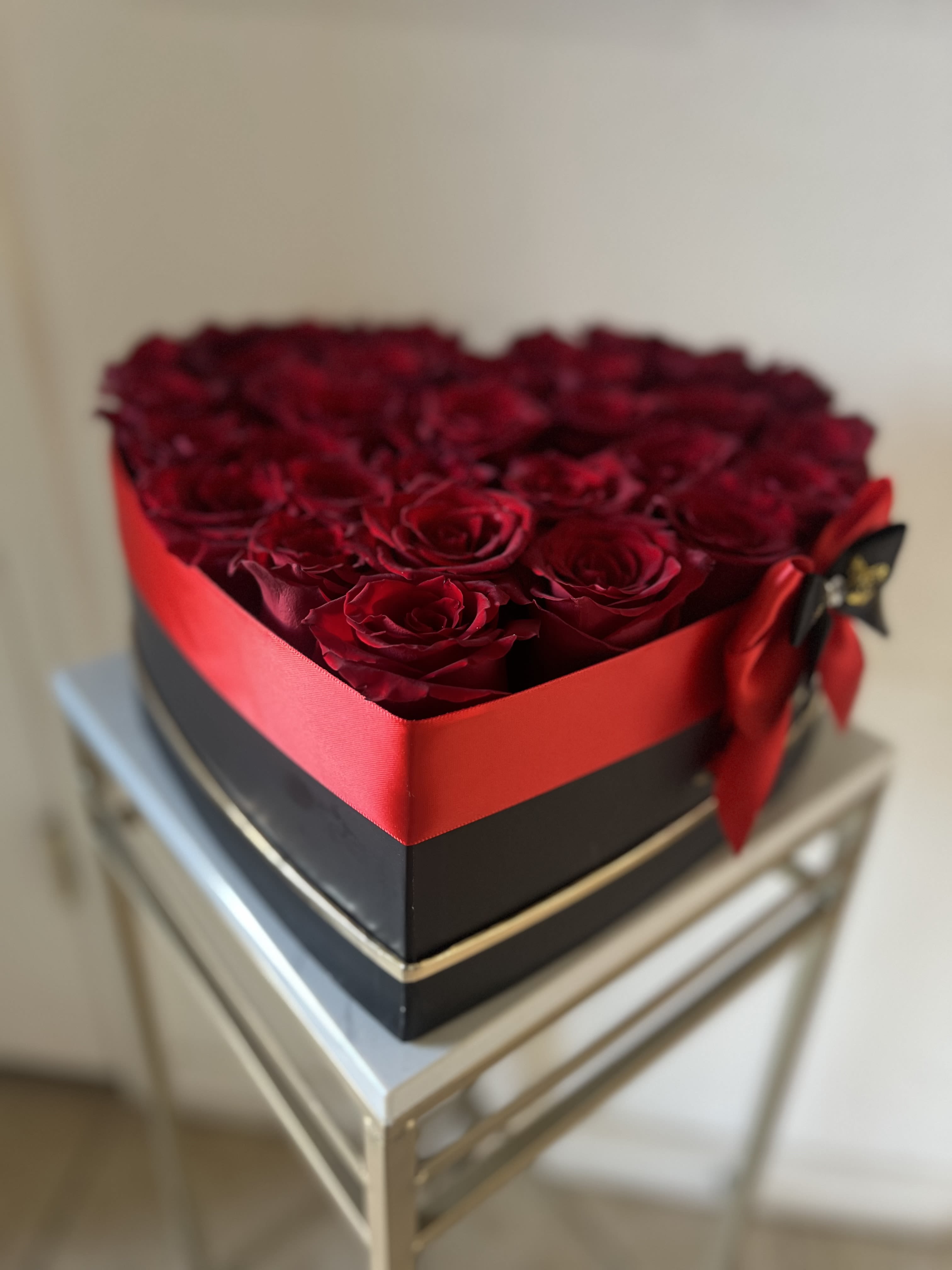 Heart-shaped box filled with red roses and tied with a red ribbon