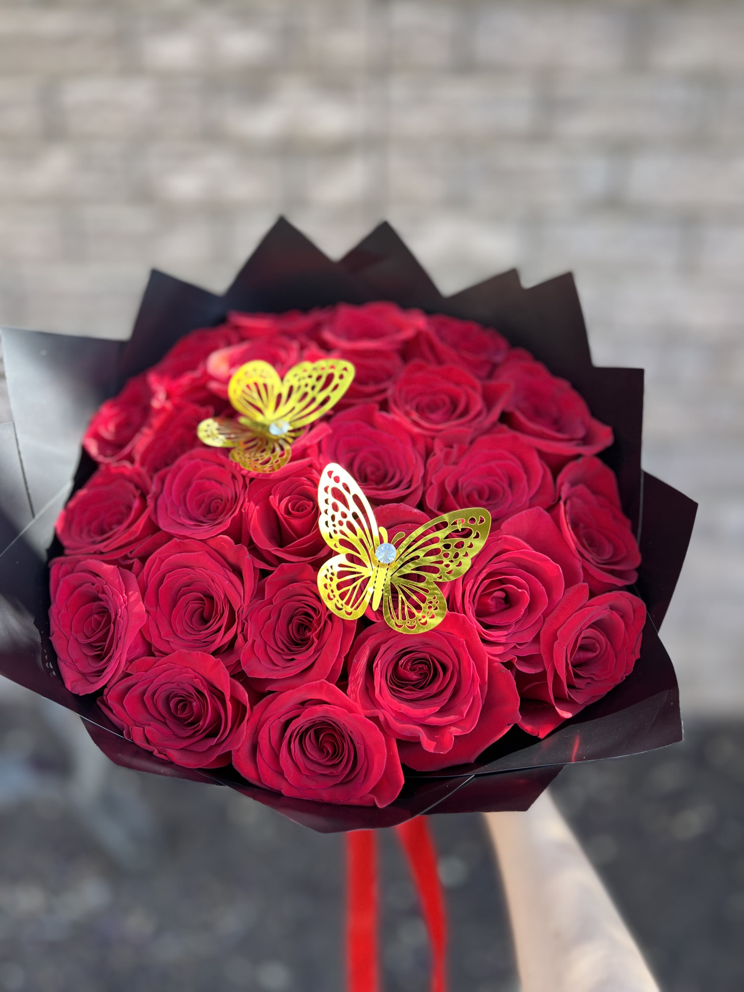 Bouquet of red roses with yellow butterfly decorations in black wrap