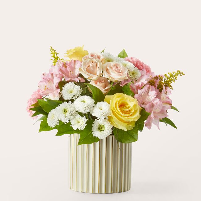 Pink and yellow flower arrangement in a gold striped vase