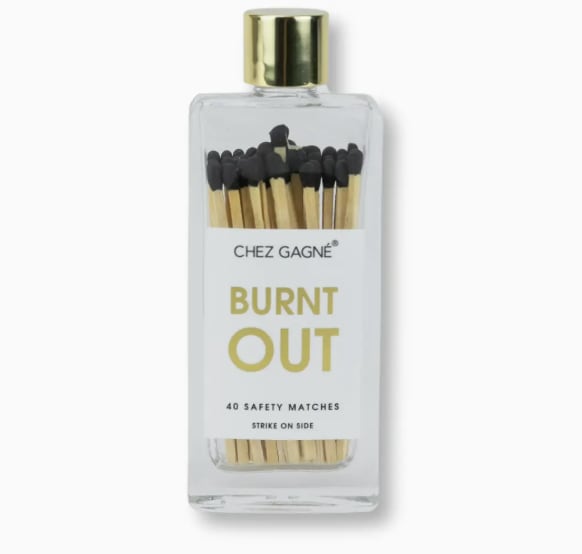 Burnt Out Glass Bottle Safety Matches (Black) - Because sometimes your vibe matches the matches. The Burnt Out safety matches are equal parts cheeky and chic, housed in a clear glass bottle with a luxe gold lid and sleek black-tipped sticks. Perfect for lighting candles, incense, or just sitting pretty on a coffee table, these matches double as functional décor with a wink.  Product details: • Glass bottle with gold lid • Size: 1.84” x 4.75” • Weight: 1.8 oz • Contains: 40 wooden safety matches with black tips • Striker on the side of the bottle
