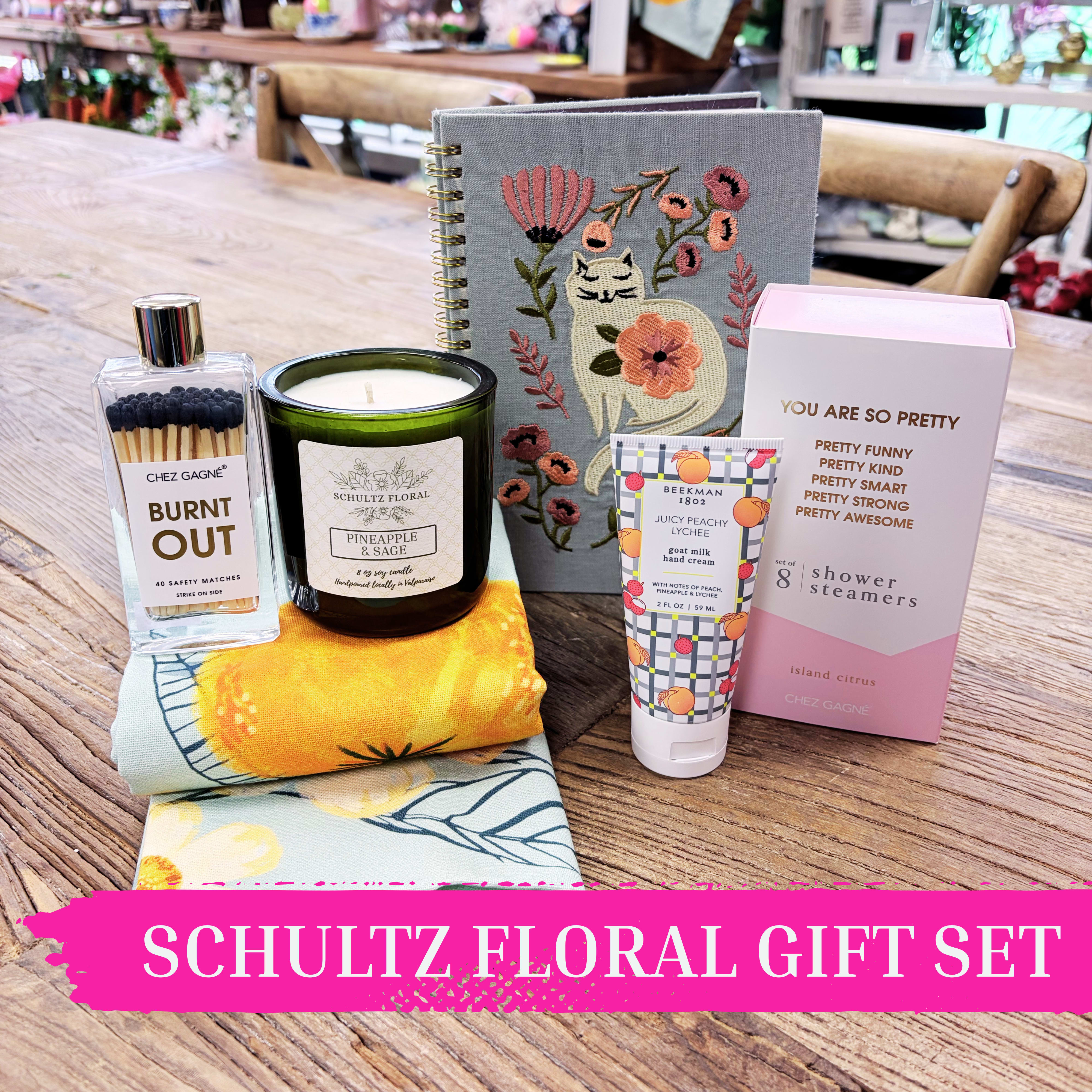 Warm Weather Whimsy Self-Care Gift Set | Fun &amp; Colorful Gift Set for Her by Schultz Floral - Celebrate sunshine, smiles, and small indulgences with this playful summer-inspired gift set. Curated for moments of pampering, it’s perfect for Mother’s Day, birthdays, or just because.  Inside this cheerful collection: – Schultz Floral hand-poured Pineapple Sage candle (8 oz) – “You’re So Pretty” Island Citrus shower steamers (set of 8) for a refreshing at-home spa experience (while supplies last; we may need to fulfill with an alternative witty set) – Burnt Out match jar, a quirky touch of practicality – Cat-embroidered lined notebook for notes, lists, or doodles – Summer-themed tea towel to brighten any kitchen – Beekman 1802 Peach Lychee Goat Milk Lotion (2 oz), a best-selling treat for soft, nourished hands  Bright, whimsical, and thoughtfully curated, this gift set brings joy and indulgence in every detail. Available for pickup or local delivery.