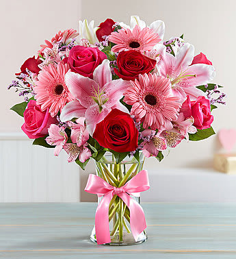 Pink and red mixed bouquet in a glass vase with a pink ribbon
