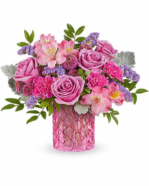 Teleflora's Pink Rhapsody Bouquet - Celebrate her in style with Pink Rhapsody Bouquet, a vibrant mix of pink and lavender blooms beautifully arranged in  Pink Rhapsody Vase. This stunning Mother's Day gift adds bold color and lasting charm to any space. Pink Rhapsody Bouquet is a vibrant Mother's Day flower arrangement featuring lavender roses, pink alstroemeria, fuchsia carnations, purple button spray chrysanthemums, and lavender sinuata statice, accented with dusty miller and huckleberry, delivered in Pink Rhapsody Vase.  Orientation: All-Around  Vase Size 5x4  Standard 3 Lavender Roses,  3 Pink Alstroemeria,  3 Pink Carnations,  1 Status  Deluxe 5 Lavender Roses,  3 Pink Alstroemeria,  3 Pink Carnations,  1 Status  Premium 7 Lavender Roses,  3 Pink Alstroemeria,  3 Pink Carnations,  1 Status