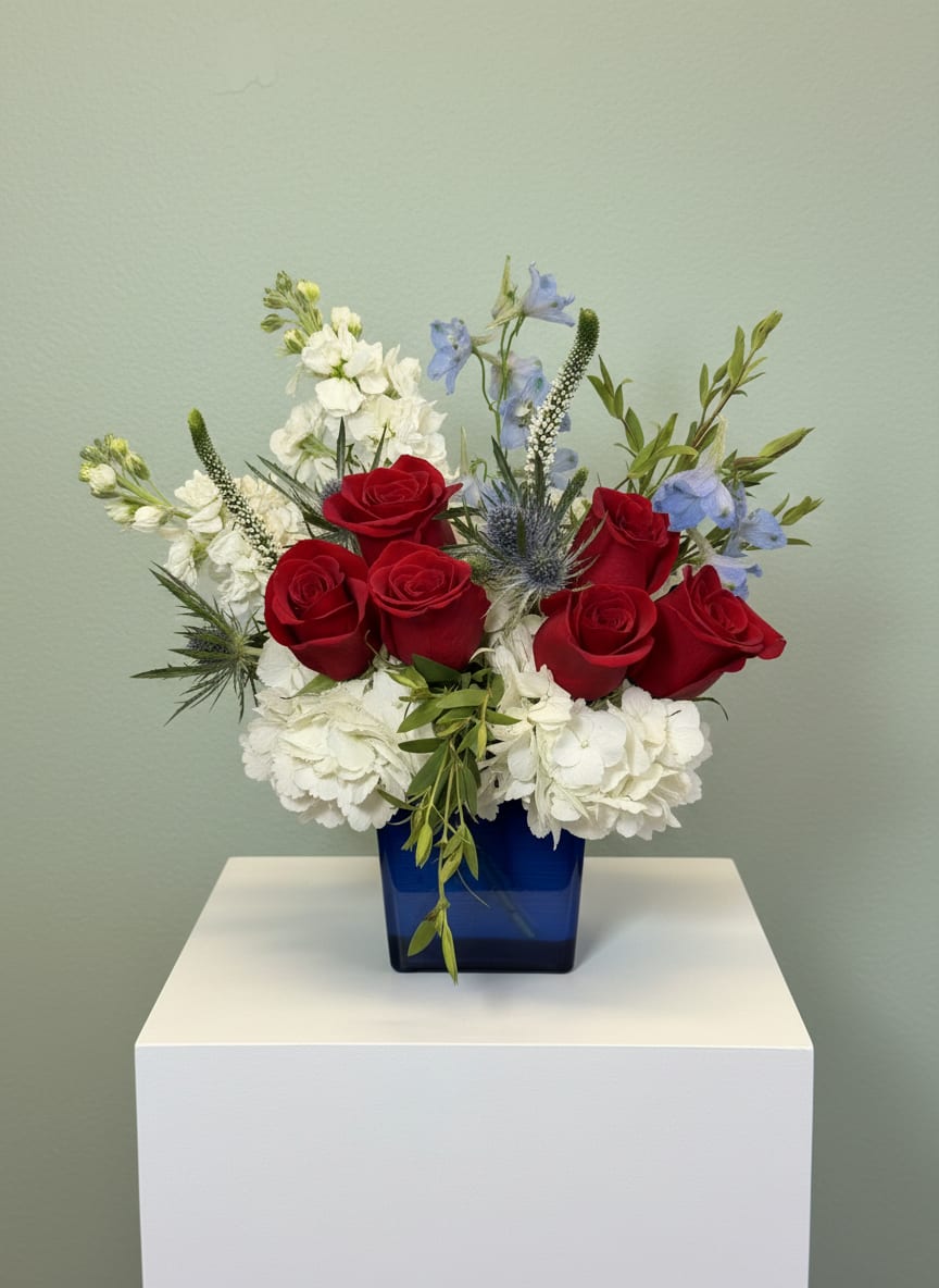 Red, White &amp; Bloom - Red, White &amp; Bloom is a timeless patriotic flower arrangement designed to celebrate the spirit of America. Handcrafted with six premium red roses, lush white hydrangeas, elegant white stock, blue delphinium, blue thistle, white veronica, and fresh seasonal greenery, this striking design is arranged in a modern 4" x 5" cobalt blue glass cube vase. Perfect for Fourth of July celebrations, Memorial Day, Veterans Day, military appreciation, summer gatherings, or as a thoughtful hostess or thank-you gift, this arrangement adds vibrant red, white, and blue beauty to any home or event. Every arrangement is carefully designed by the floral artisans at All Occasions Florist using the freshest flowers available for exceptional quality and long-lasting enjoyment. We proudly offer same-day flower delivery throughout Dallas, Richardson, Plano, Garland, Highland Park, University Park, Lake Highlands, Mesquite, and surrounding DFW communities. Order Red, White &amp; Bloom today for a beautiful patriotic floral gift delivered with care.