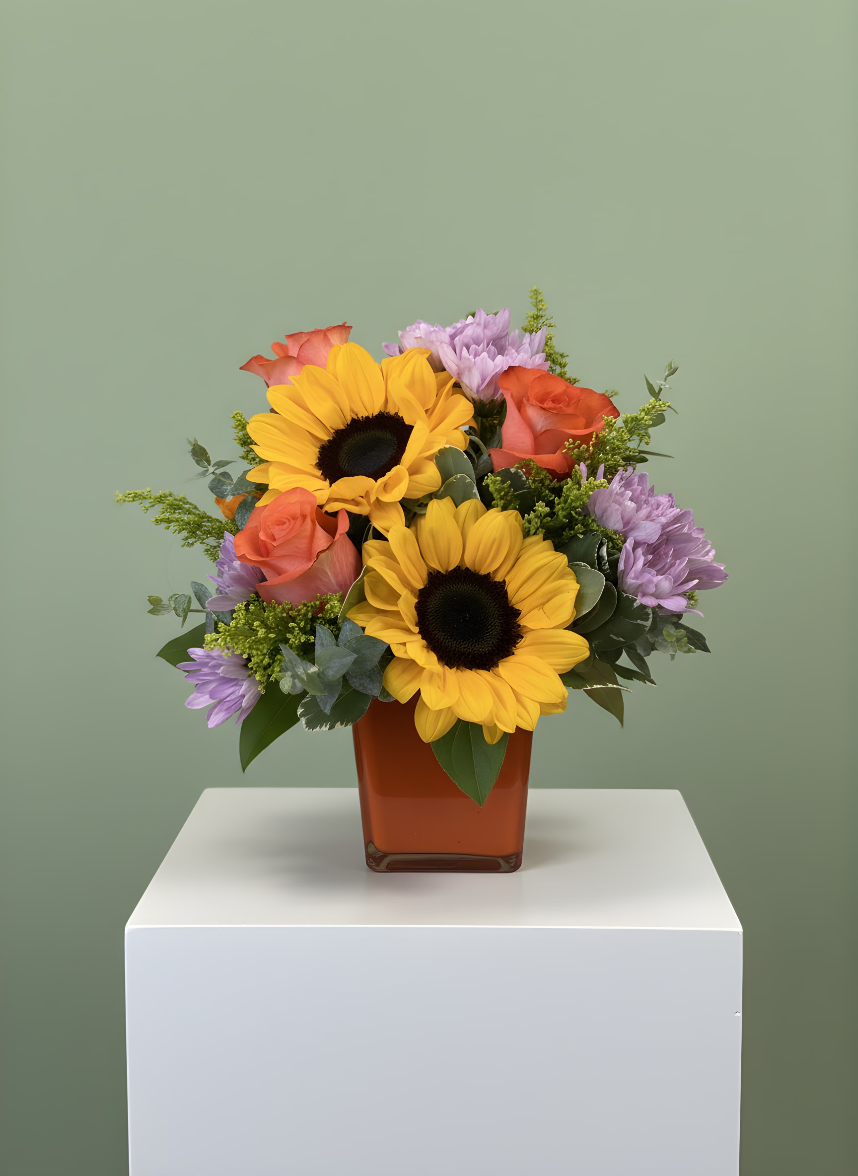 Sunkissed - Sunkissed is a bright and cheerful floral arrangement that captures the beauty of summer. Designed in a modern 4" x 5" colored glass cube vase, this handcrafted arrangement features vibrant sunflowers, premium peach roses, lavender chrysanthemums, fresh seasonal greenery, and complementary accent flowers for a warm, garden-inspired look. Perfect for birthdays, thank-you gifts, get well wishes, anniversaries, housewarmings, or simply brightening someone's day, Sunkissed brings sunshine to any occasion. Every arrangement is professionally designed by the floral artisans at All Occasions Florist using the freshest flowers available for long-lasting beauty and exceptional quality. We proudly offer same-day flower delivery throughout Dallas, Richardson, Plano, Garland, Highland Park, University Park, Lake Highlands, Mesquite, and surrounding DFW communities. Order Sunkissed today for a fresh sunflower arrangement that delivers warmth, happiness, and the beauty of the season to someone special.