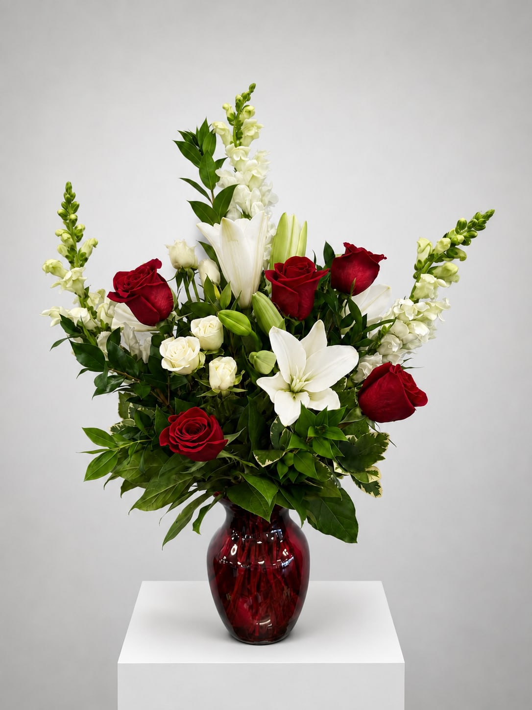 Red and white floral arrangement in a red glass vase