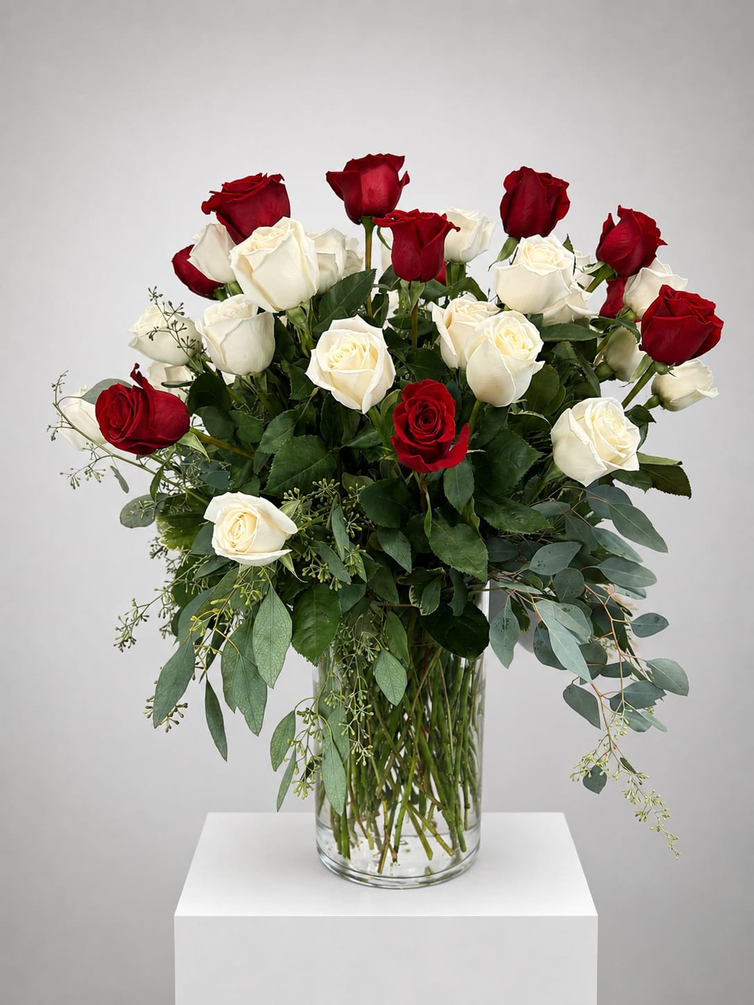 Red and white roses arranged in a clear glass vase