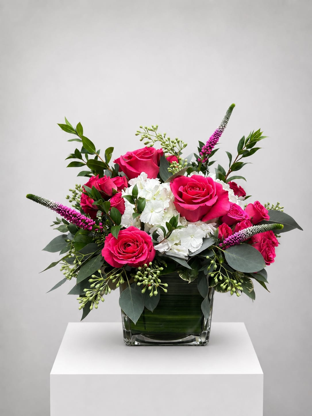 Pink roses and white hydrangeas in a glass vase with greenery