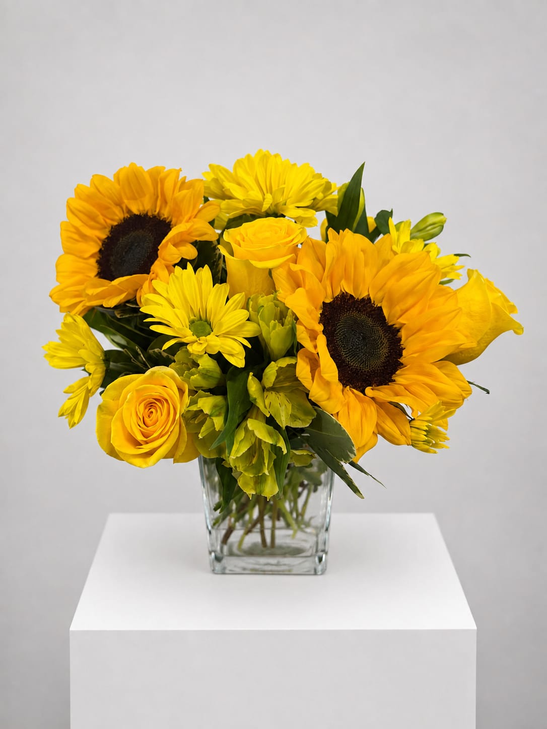 Yellow sunflower and rose bouquet in a clear glass vase