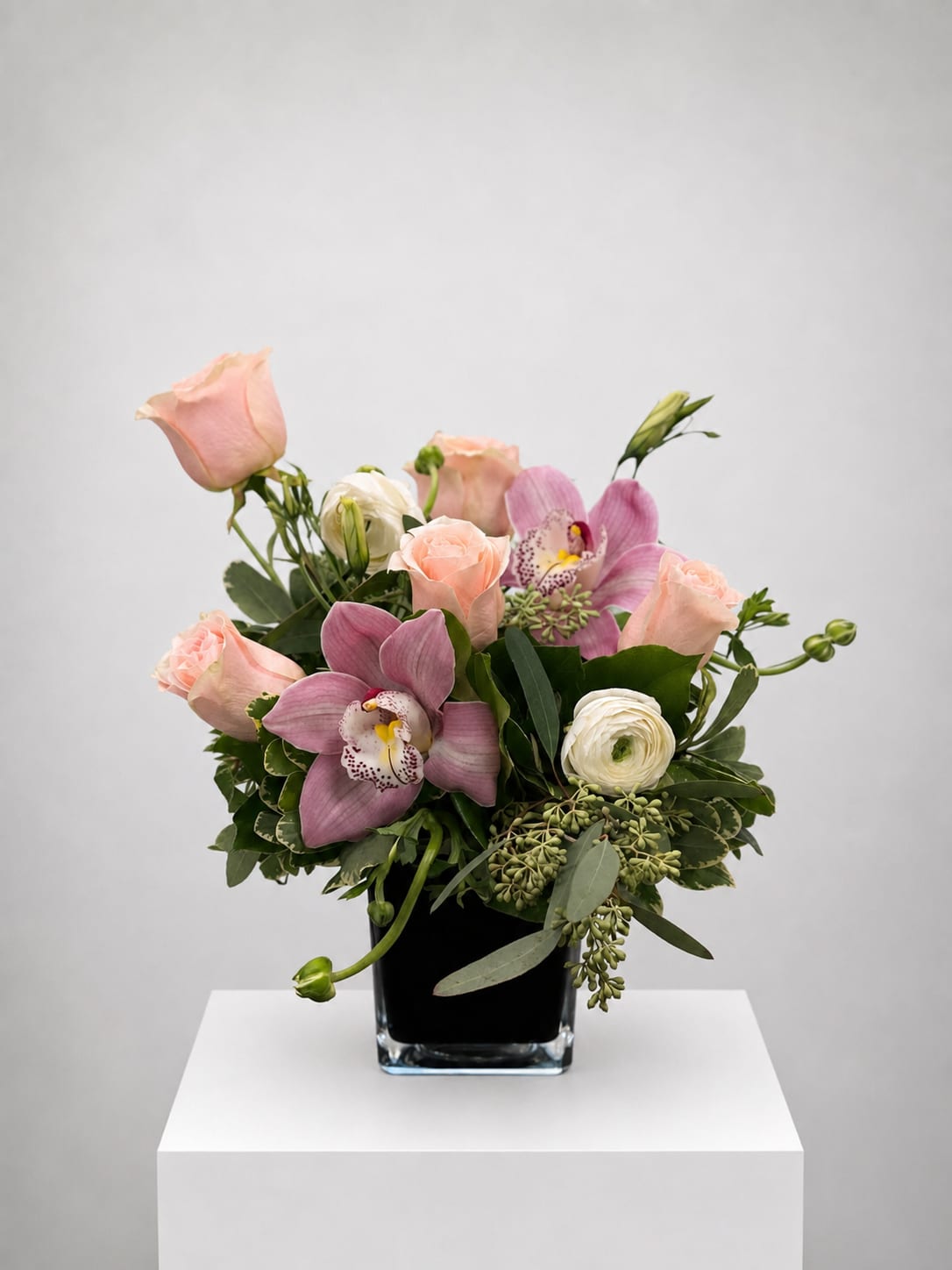 Pink roses and orchids arranged in a black vase