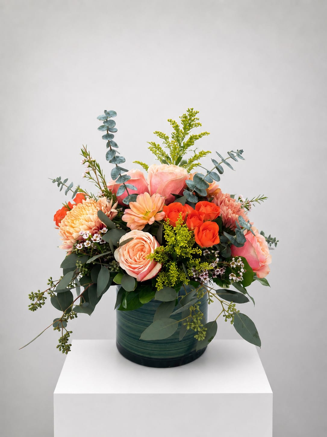 Peach and orange rose bouquet in a green vase
