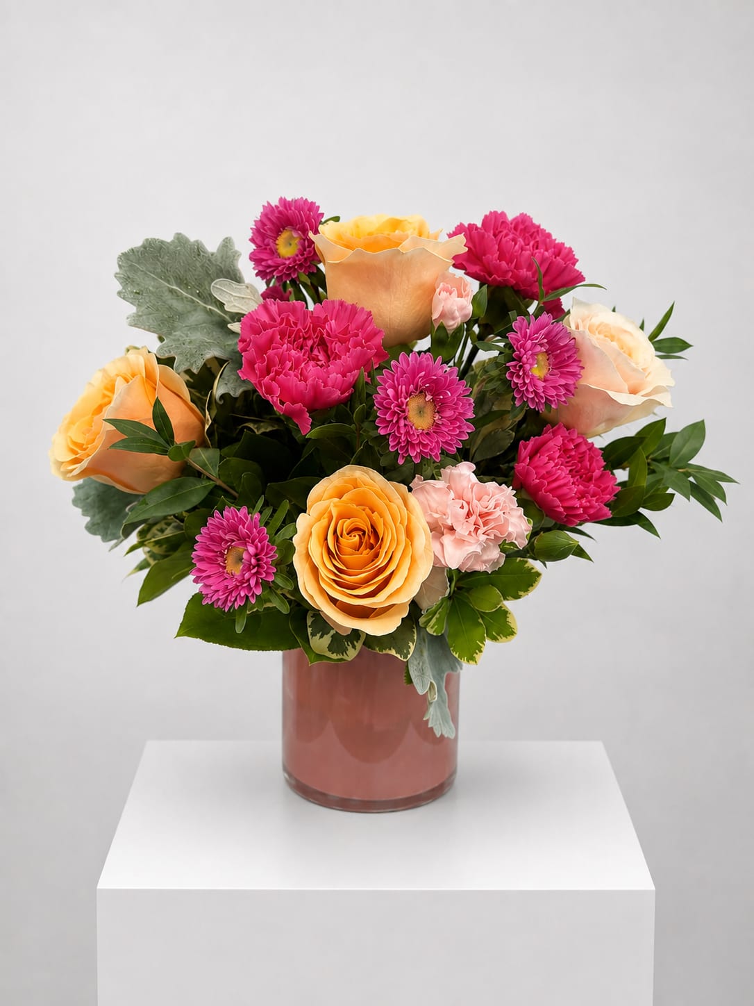 Bouquet of peach roses and pink daisies in a glass vase