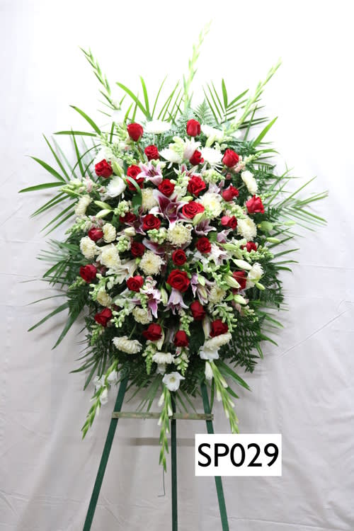 Large standing floral spray with red and white flowers on a green easel