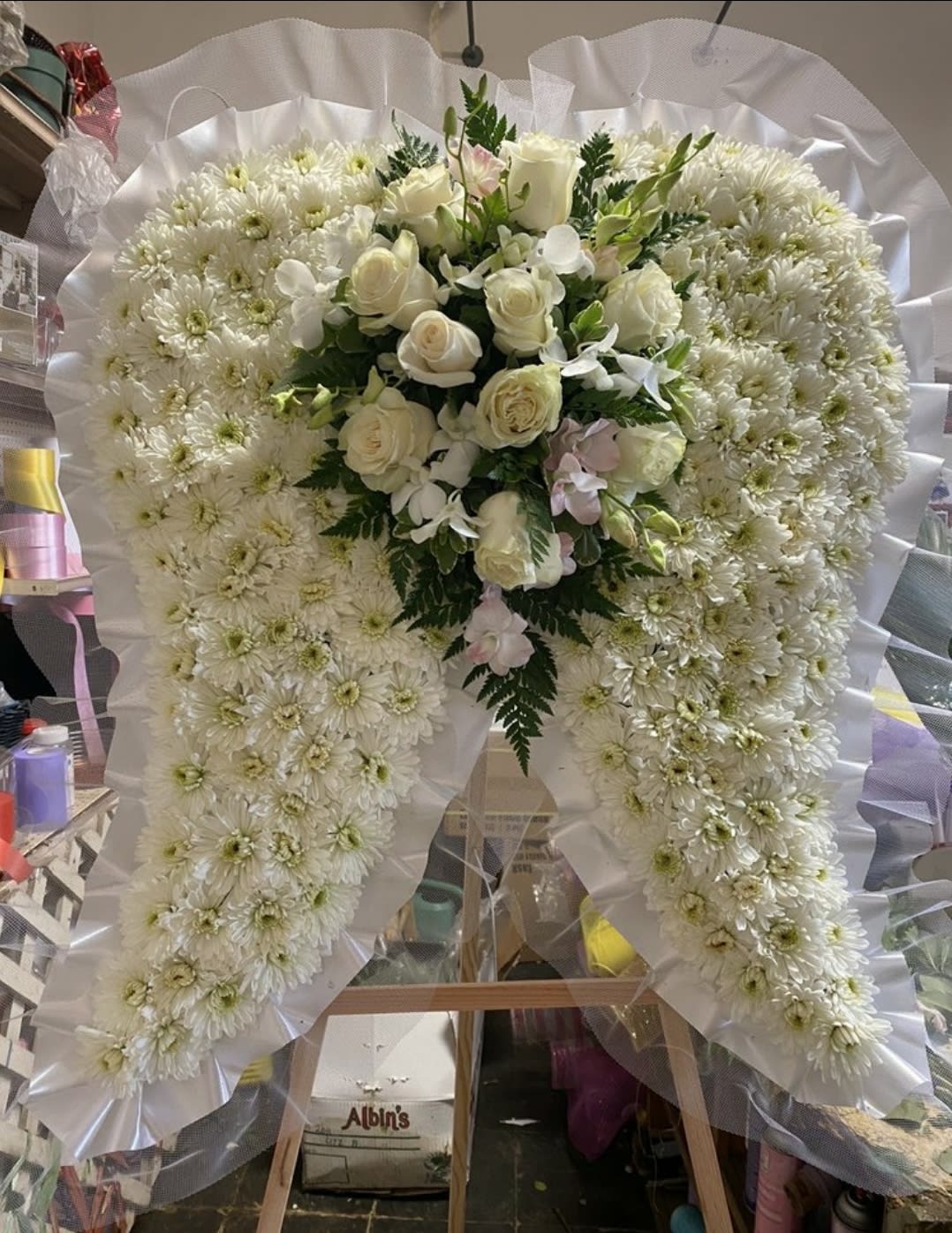White floral standing spray with roses and chrysanthemums on an easel