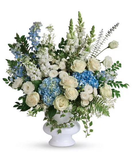White and blue floral arrangement in a white pedestal vase