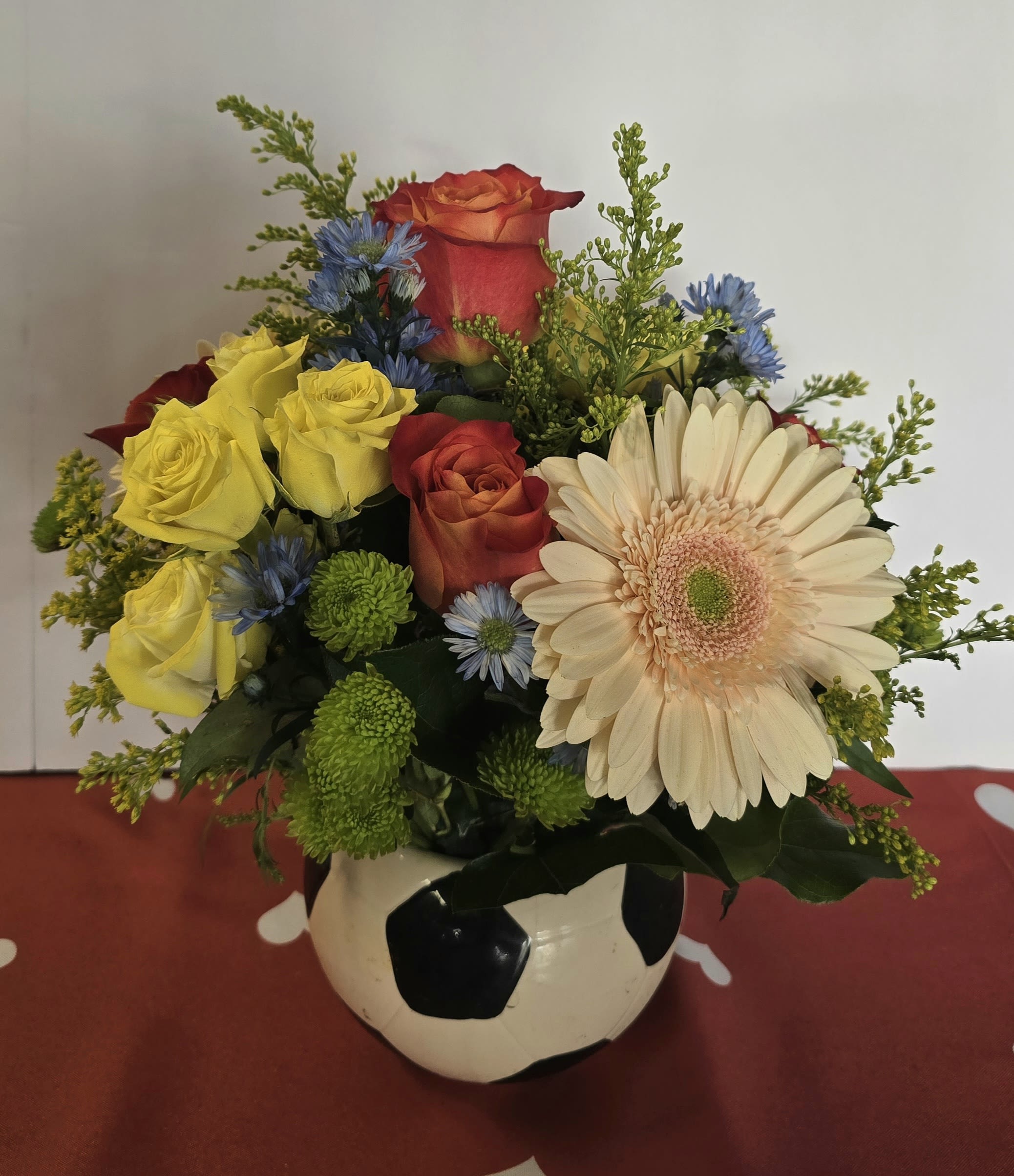 Mixed bouquet in a soccer ball vase with roses and a gerbera daisy