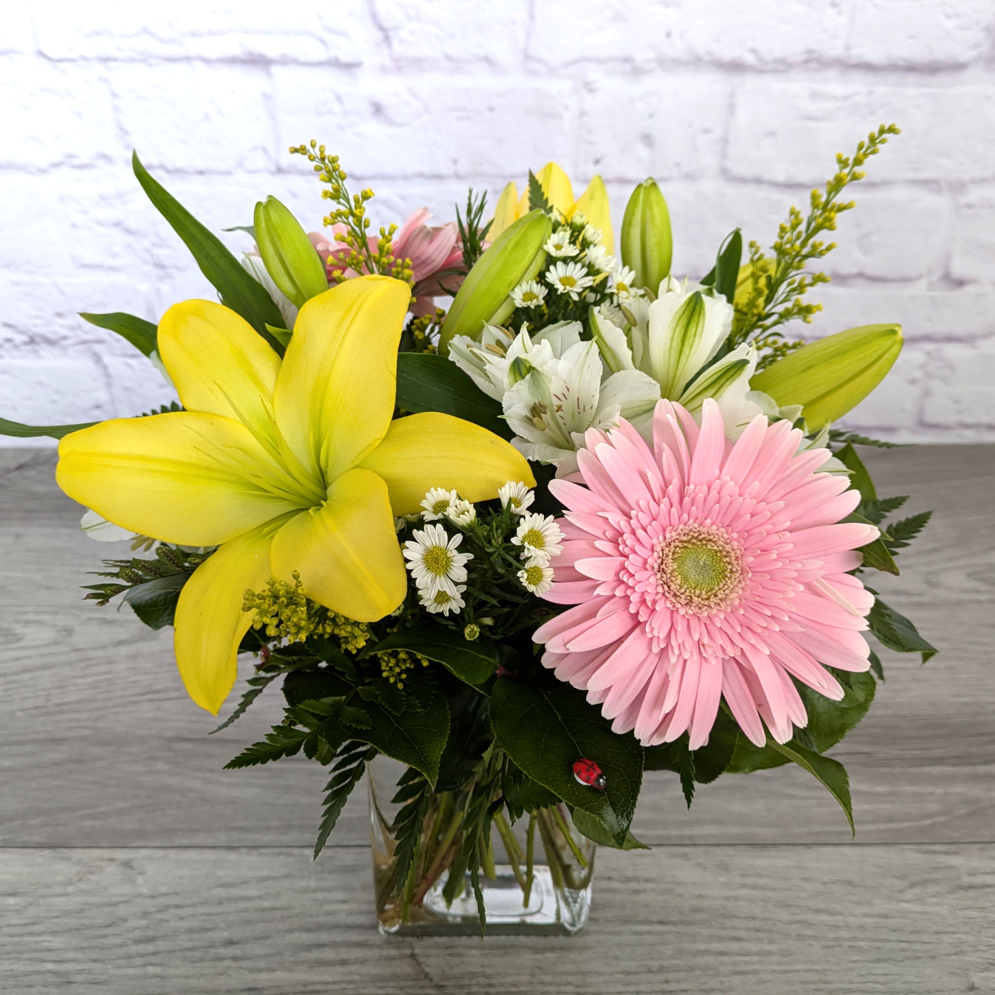 Bouquet of yellow lilies, pink gerbera daisies, and white alstroemeria in a glass vase