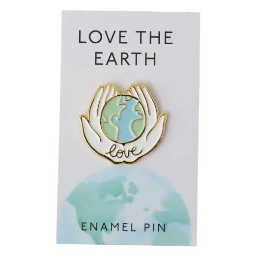 Enamel pin on a card with hands holding the Earth and the words Love the Earth