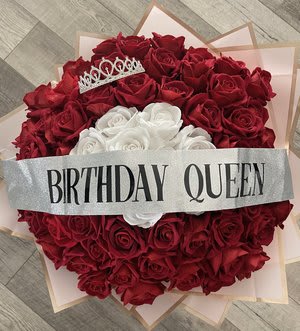 Heart-shaped bouquet of red and white roses with a birthday queen ribbon