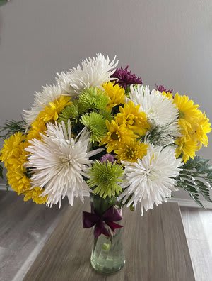 Bouquet of white, yellow, and green chrysanthemums in a glass vase